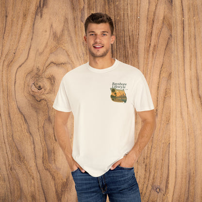 Bayshore Lifestyle Tee - Front view of a man wearing a lightweight, 100% cotton t-shirt with a scenic graphic, set against a wooden background.