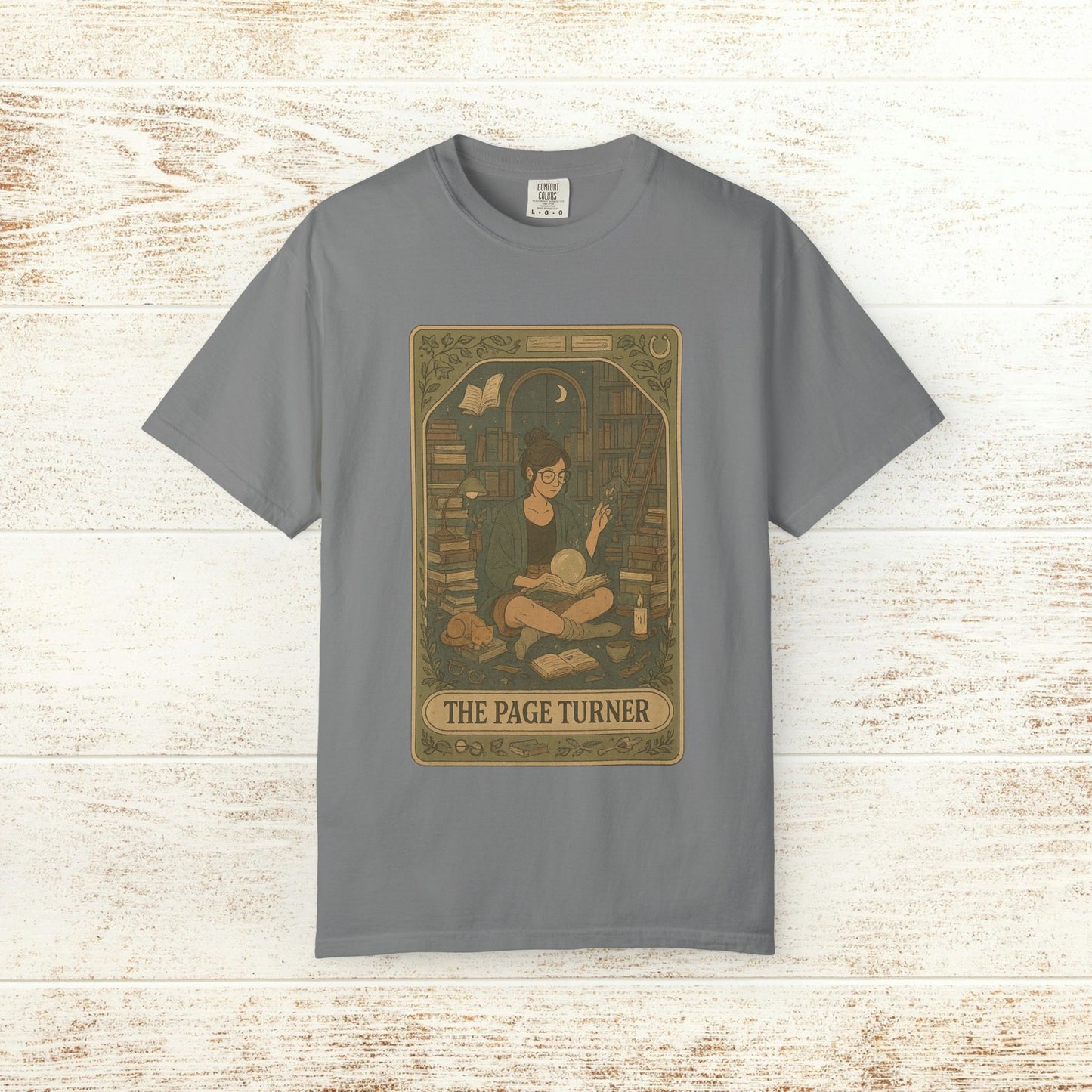 Page Turner Tarot Tee in gray, showcasing a cozy illustration of a book lover in a library, made from comfortable and sustainable cotton, offered in sizes S to 4XL.