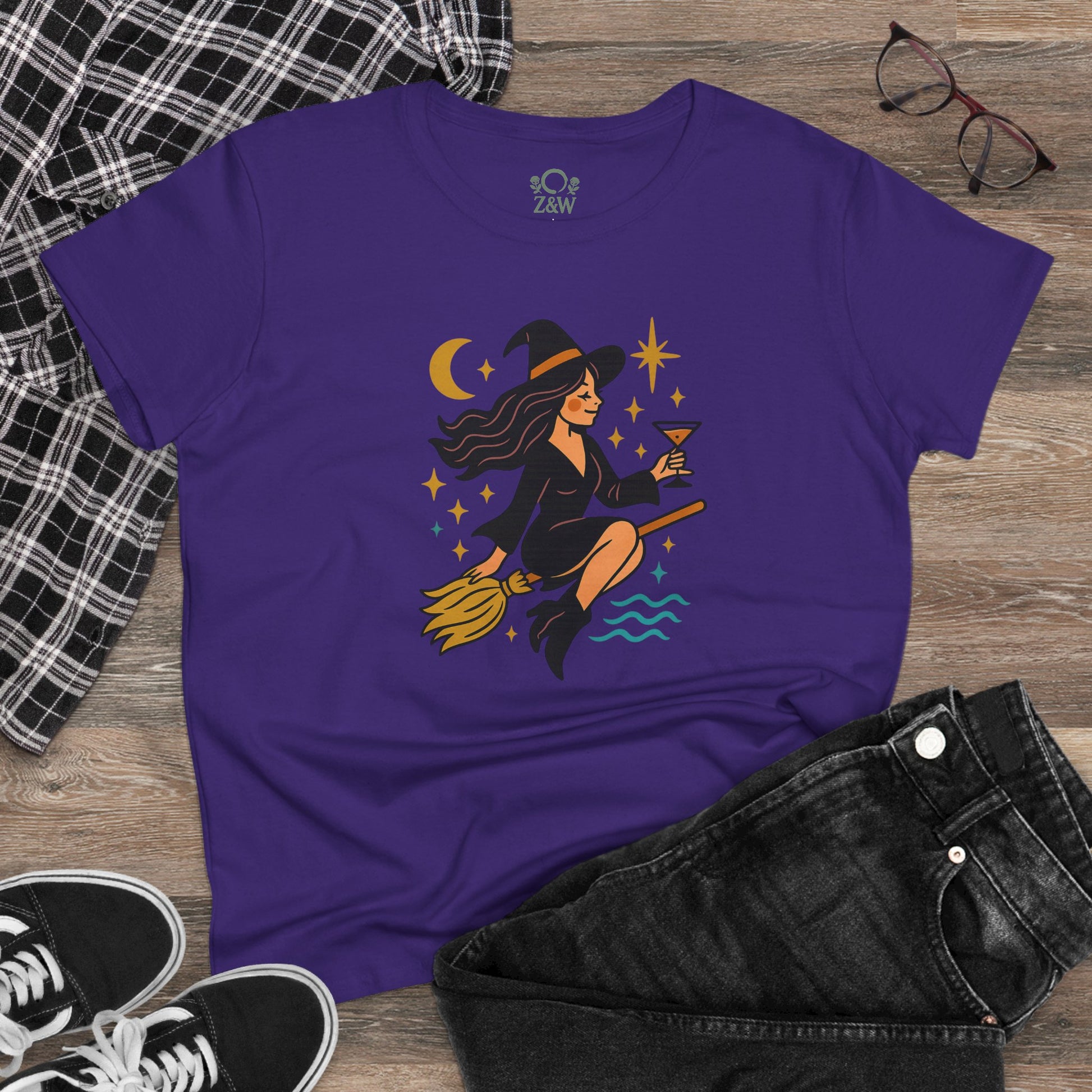 Witchy Night Out Tee displayed with casual outfit accessories, in purple featuring a witch graphic, ideal for any stylish occasion.