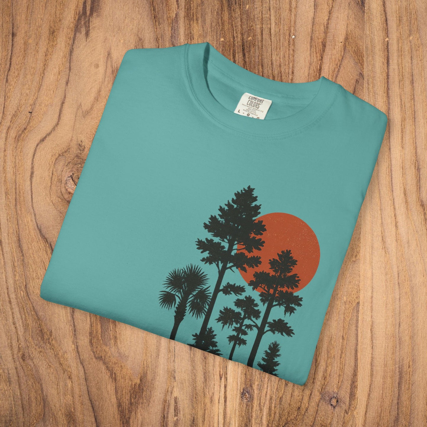 Folded Sunset Trees Unisex T-Shirt featuring a vibrant tree and sun design, made from soft 100% cotton, perfect for nature lovers seeking stylish comfort.