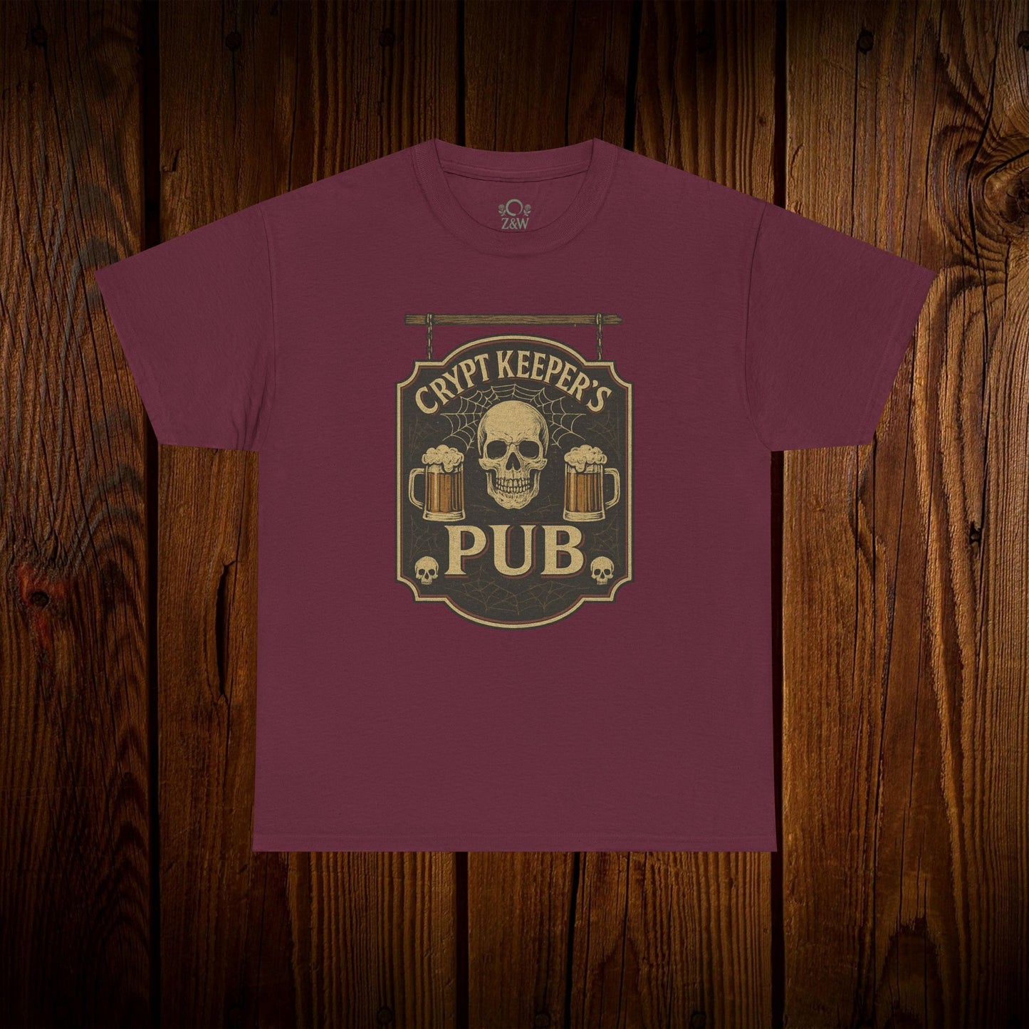 Crypt Keeper's Pub Tee in a rich burgundy color, showcasing a skull and beer mugs graphic, great for festive gatherings and casual outings.