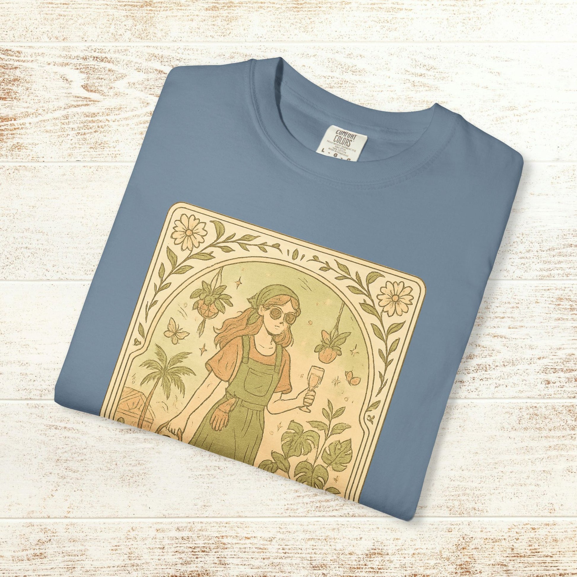 Rooted One Tarot Tee in light blue, presenting a unique illustration of a girl amid plants and butterflies, made from ethically sourced cotton, available in sizes S-4XL.