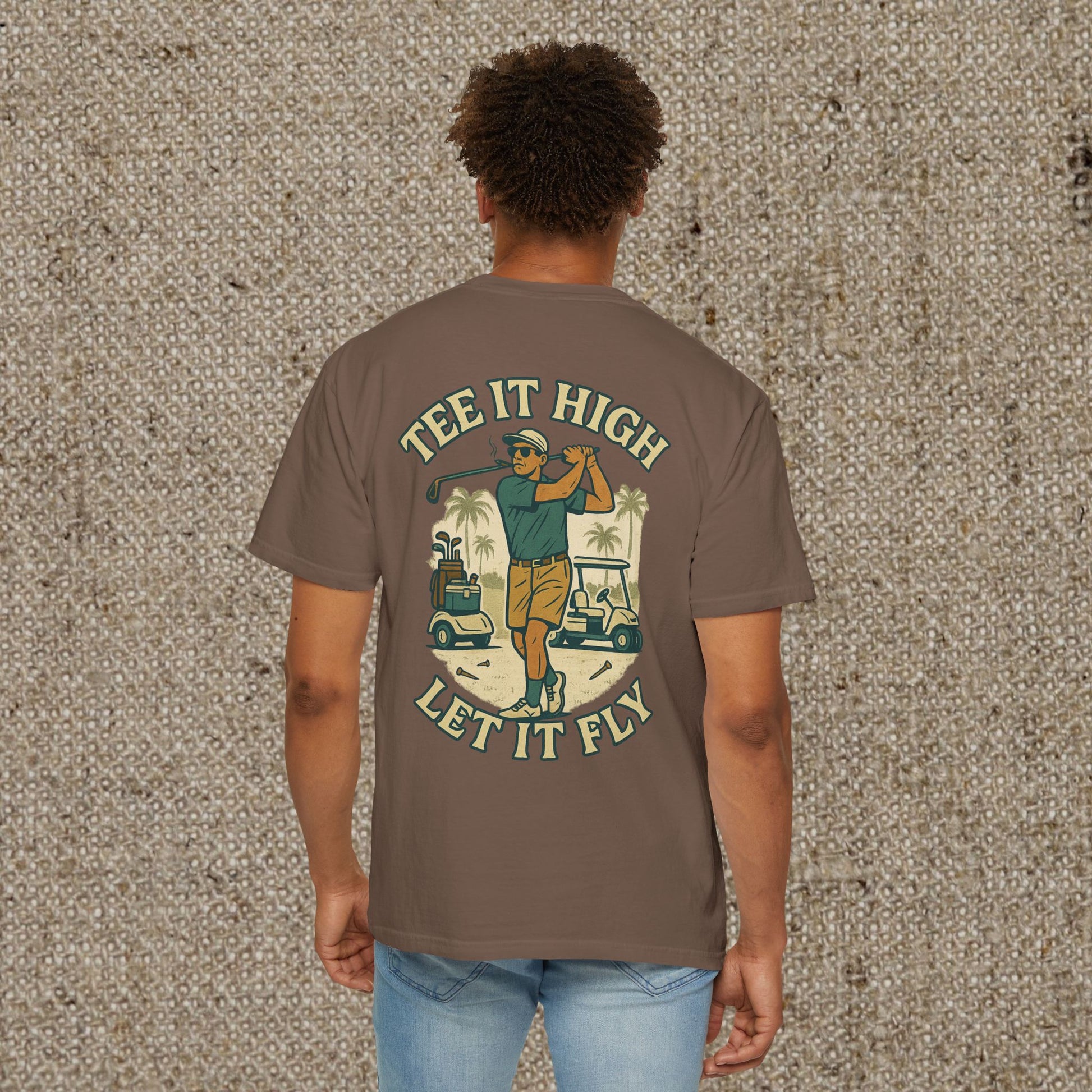 Tee It High Let It Fly Graphic Tee in brown, displaying a golfer's back swing with palm trees and golf carts. A must-have for avid golfers.