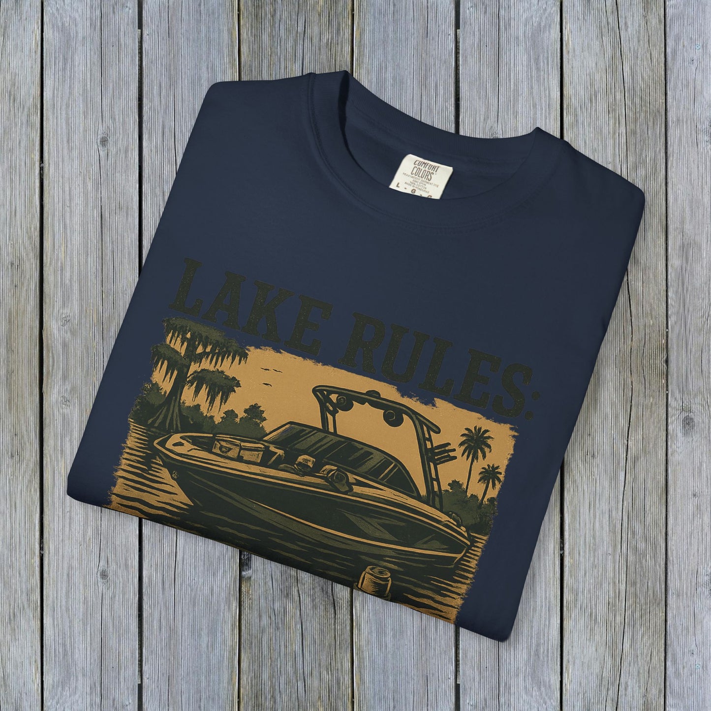 Front view of the folded Unisex Garment-Dyed Lake Rules Tee with a boat graphic, perfect for lake lovers and outdoor enthusiasts.