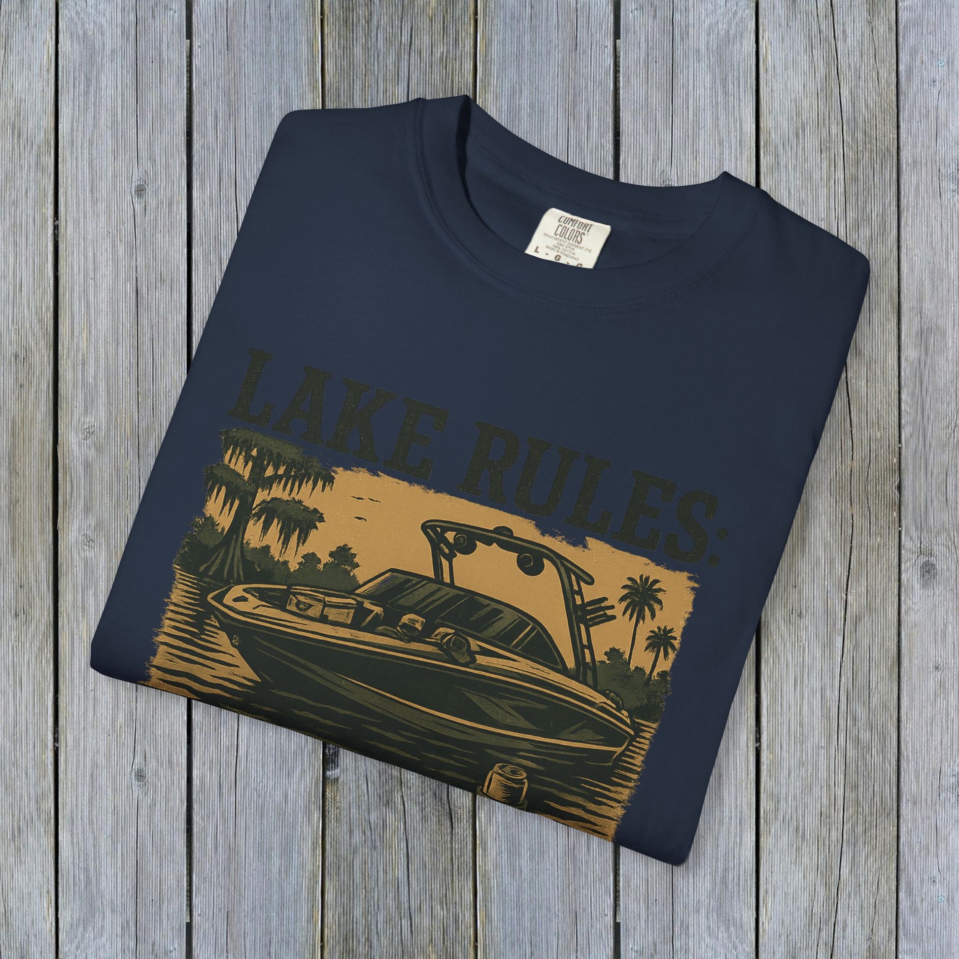 Front view of the folded Unisex Garment-Dyed Lake Rules Tee with a boat graphic, perfect for lake lovers and outdoor enthusiasts.