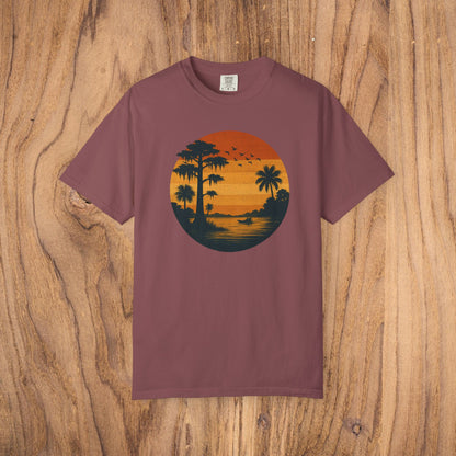 Unisex Garment-Dyed Sunset Tee in rich maroon featuring a beautiful sunset scene with palm trees and birds. Soft 100% cotton fabric available in sizes S to 4XL.
