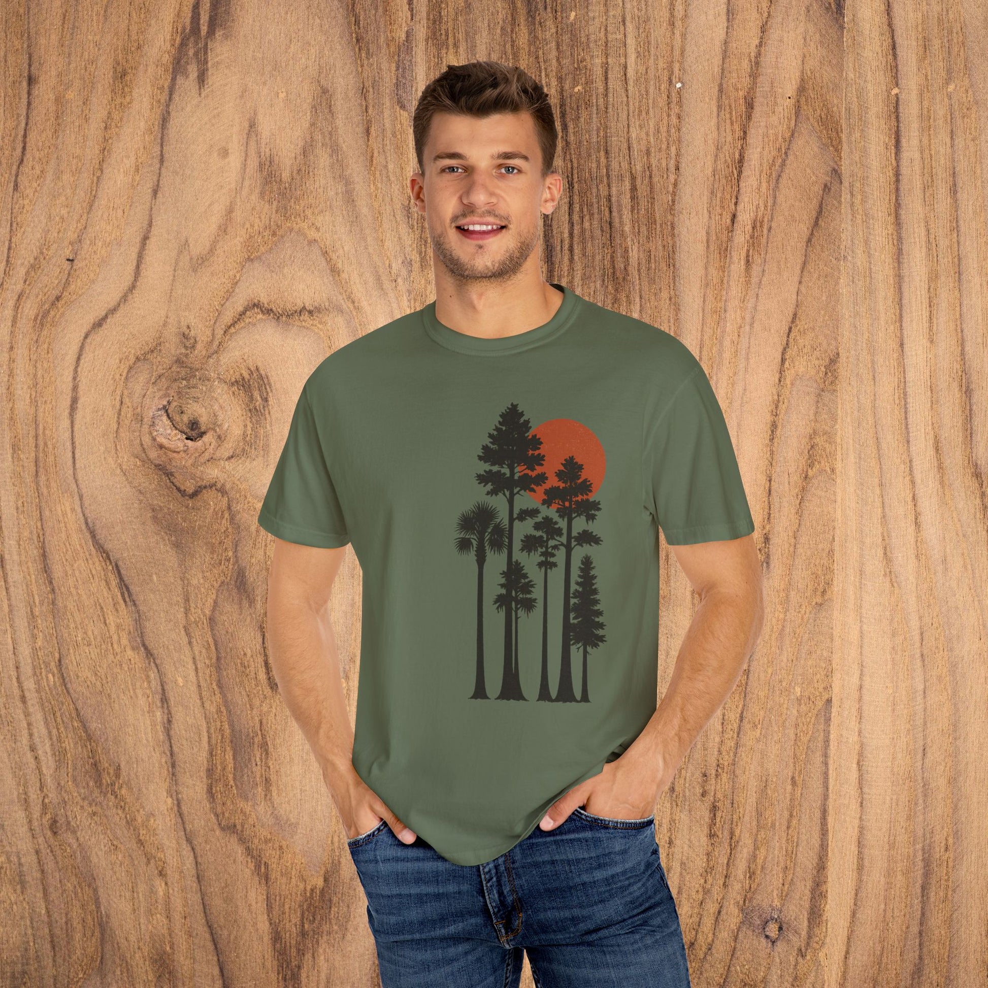Sunset Trees Unisex T-Shirt model posing in olive green featuring a beautiful tree silhouette and sunset, great for outdoor enthusiasts.