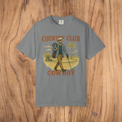 Country Club Cowboy Graphic Tee in gray, depicting a cowboy walking with golf clubs in a serene landscape. This durable cotton tee features a ribbed collar for lasting quality.