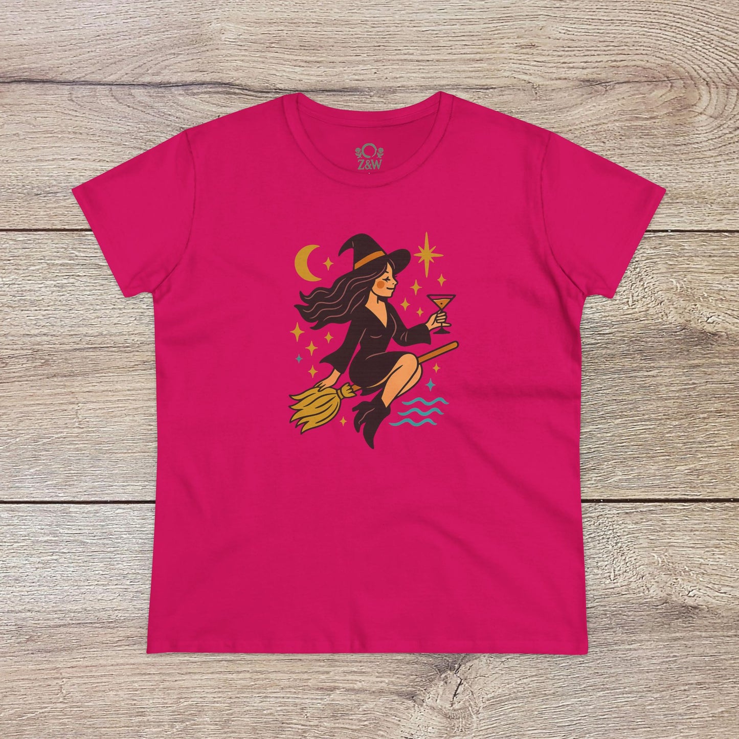 Witchy Night Out Tee displayed in bright pink showcasing a playful witch with a martini on her broomstick against a starry background, made from ethical and sustainable materials.