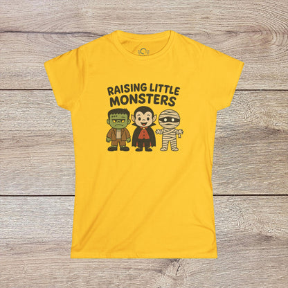 Bright yellow Halloween Family T-Shirt with playful illustrations of a Frankenstein monster, Dracula, and a mummy, along with 'Raising Little Monsters' text. Great kids tee for Halloween festivities.
