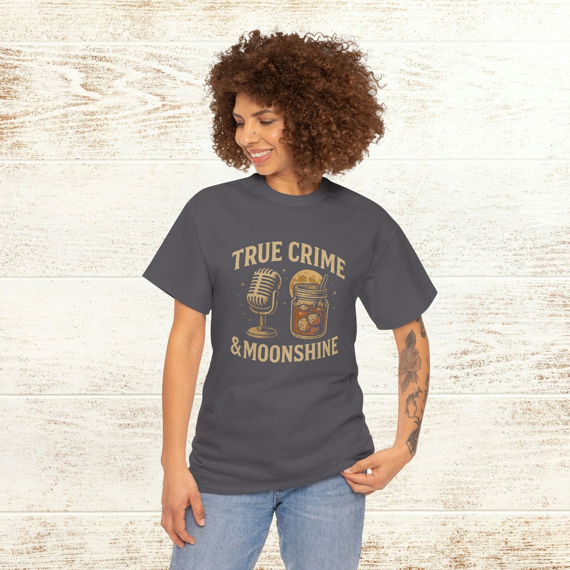 Front view of a model wearing the True Crime & Moonshine Unisex Graphic Tee in gray, featuring a microphone and a moonshine jar design, ideal for casual outings.
