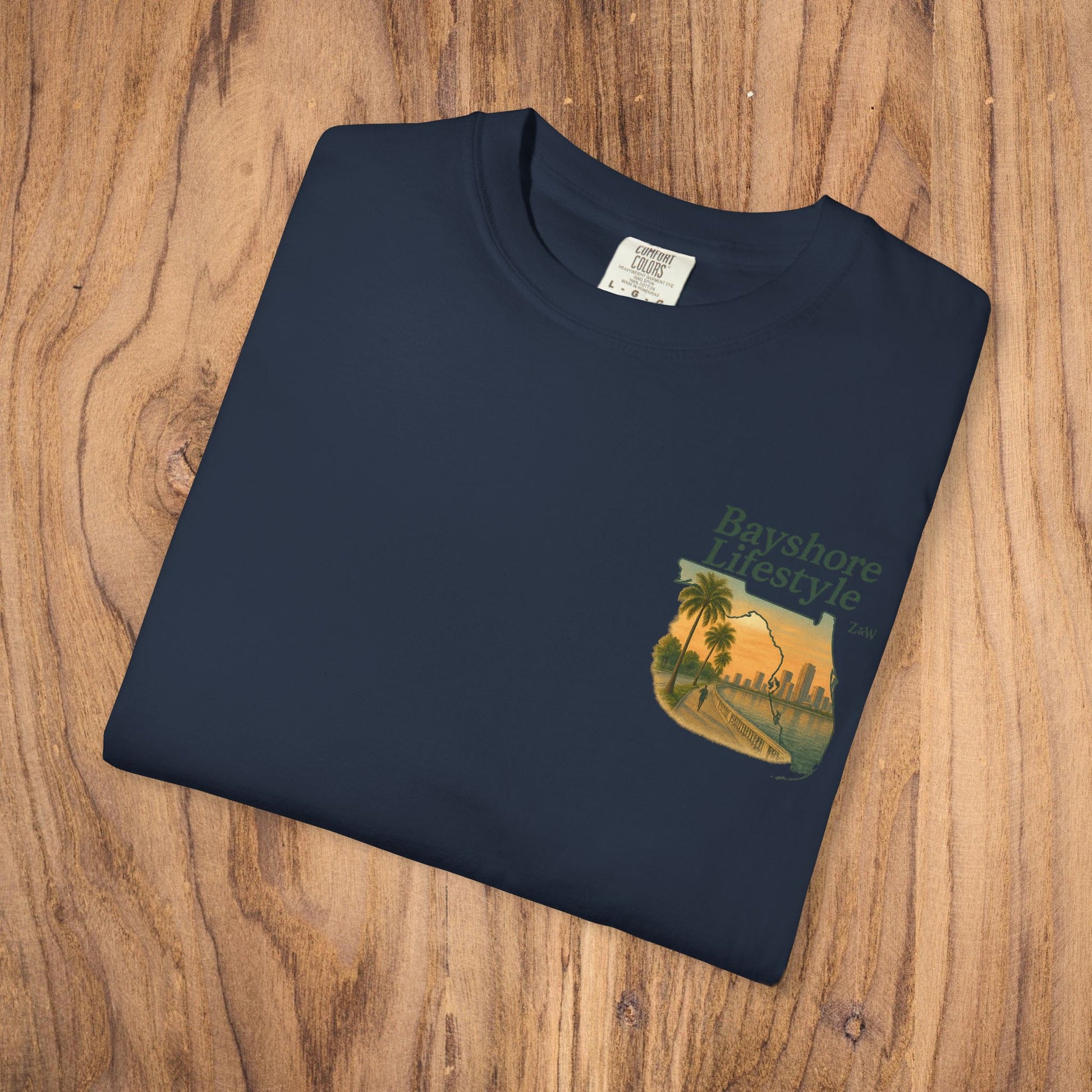 Bayshore Lifestyle Tee in navy, folded on a wooden surface, featuring the unique palm tree graphic, emphasizing its lightweight and breathable fabric.