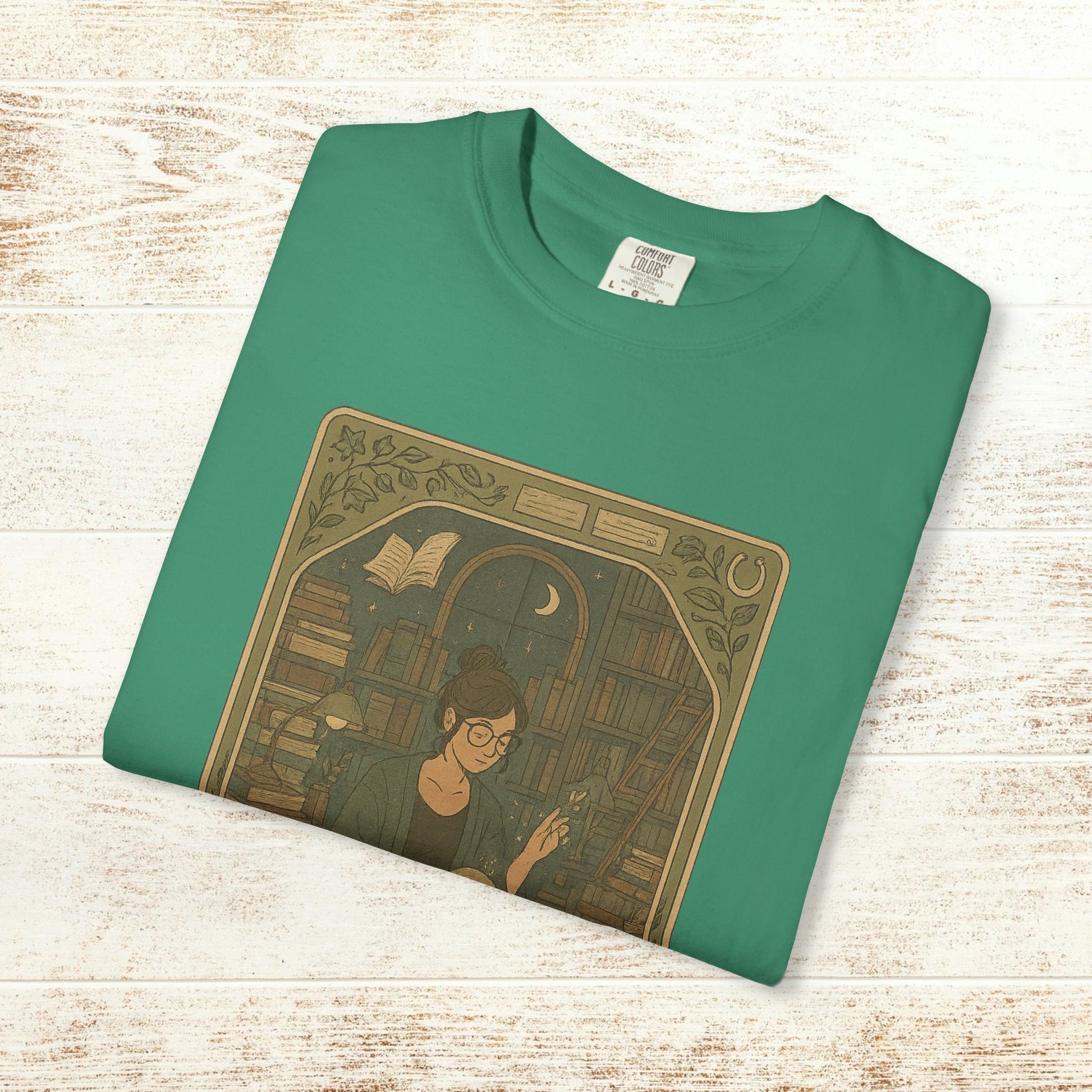 Page Turner Tarot Tee in teal color displaying a charming graphic of a woman surrounded by books, crafted from soft cotton, offered in sizes S to 4XL, eco-friendly and comfortable.