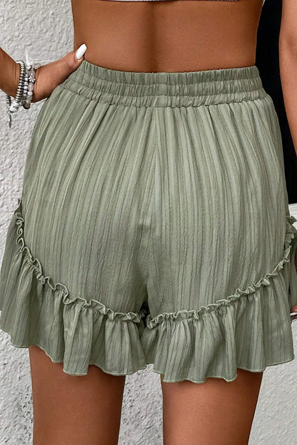 Back view of Textured Tie Waist Ruffle Hem Shorts in soft green with an elastic waistband and flowing ruffle detail, ideal for casual comfort.