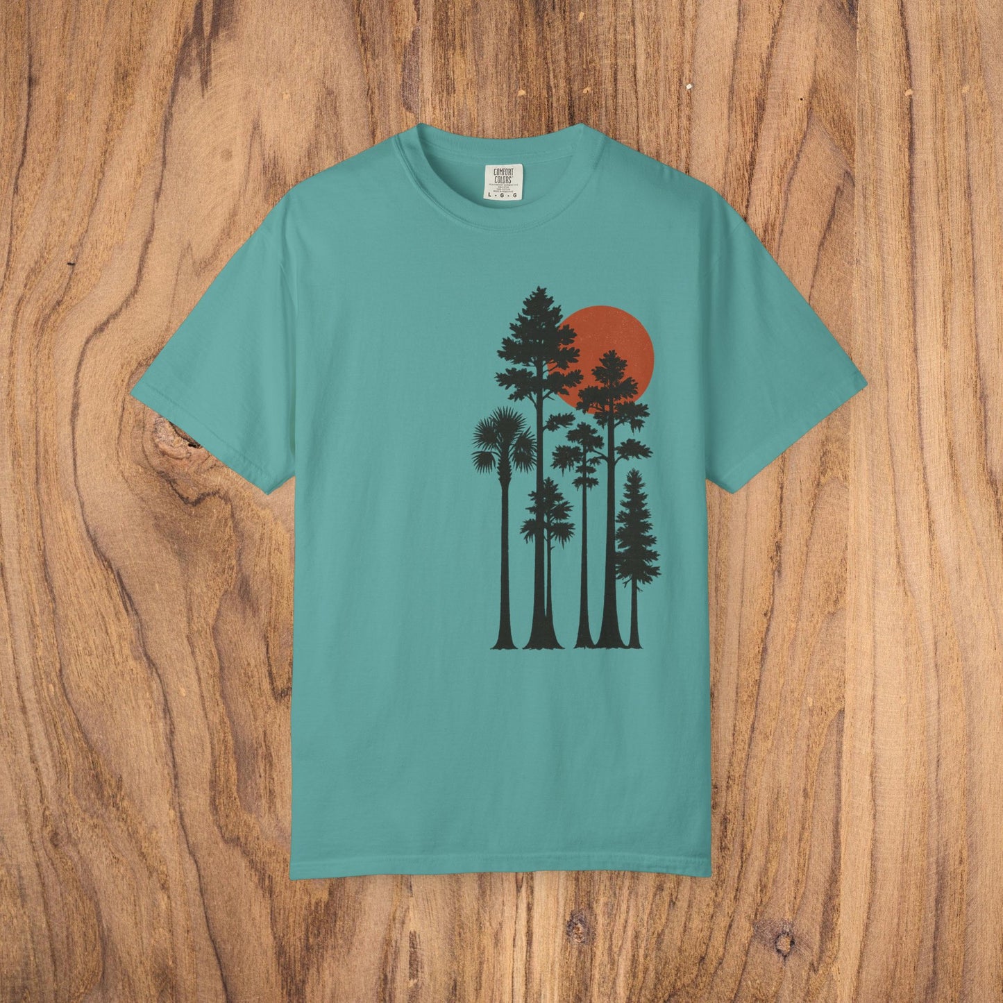 Sunset Trees Unisex T-Shirt in teal, illustrating a tranquil scene with trees and a red sunset, made with 100% ring-spun cotton for a soft, durable fit.