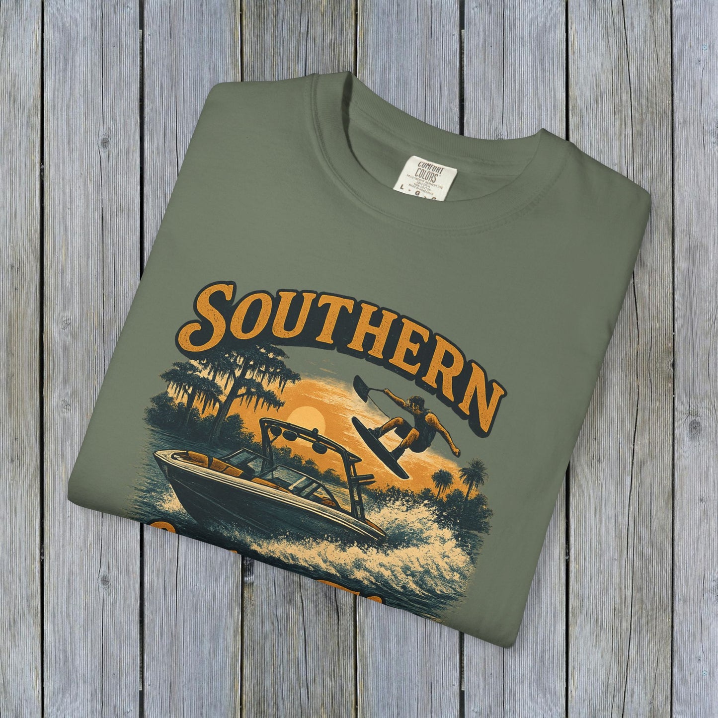 Southern Lake Flow T-Shirt in olive green, featuring a colorful design of a wakeboarder and boat, made from eco-friendly 100% US cotton for a comfortable and stylish fit.