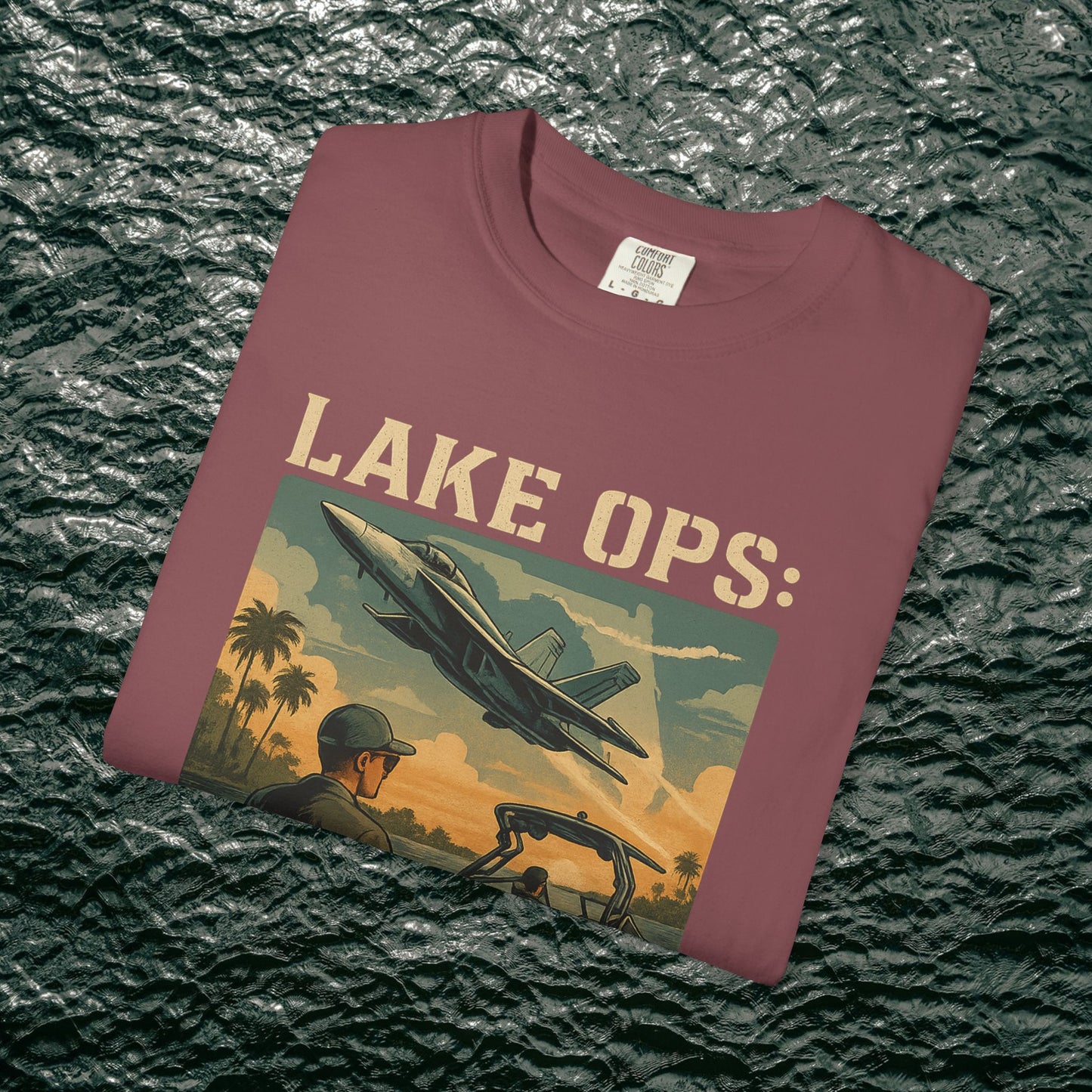 Folded Garment-Dyed Comfort Tee For Adults in maroon featuring the 'Lake Ops: Whiskey on Deck' print, perfect for outdoor occasions.