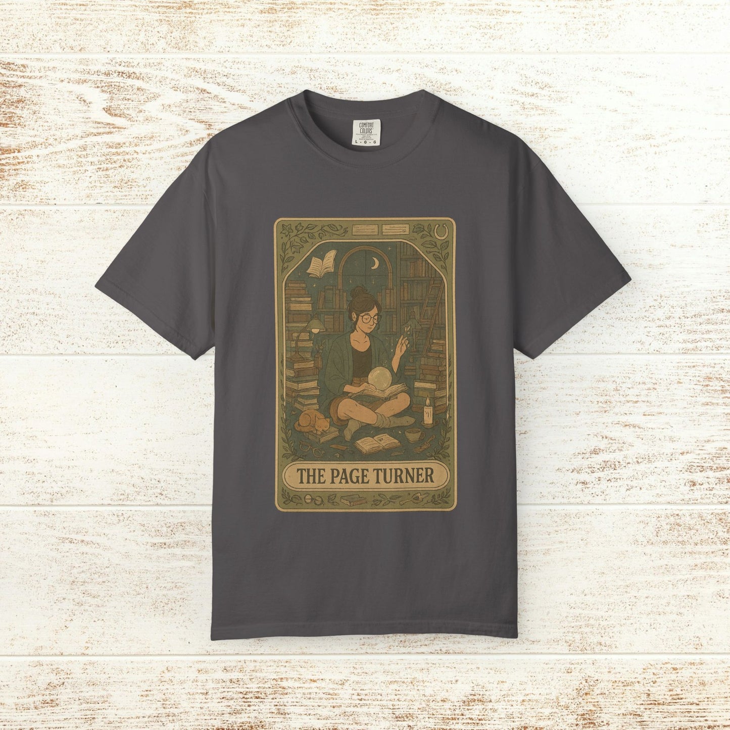 Page Turner Tarot Tee - Soft Cotton T-Shirt featured in dark gray, showcasing a whimsical design with a character surrounded by books, perfect for book lovers and tarot enthusiasts.