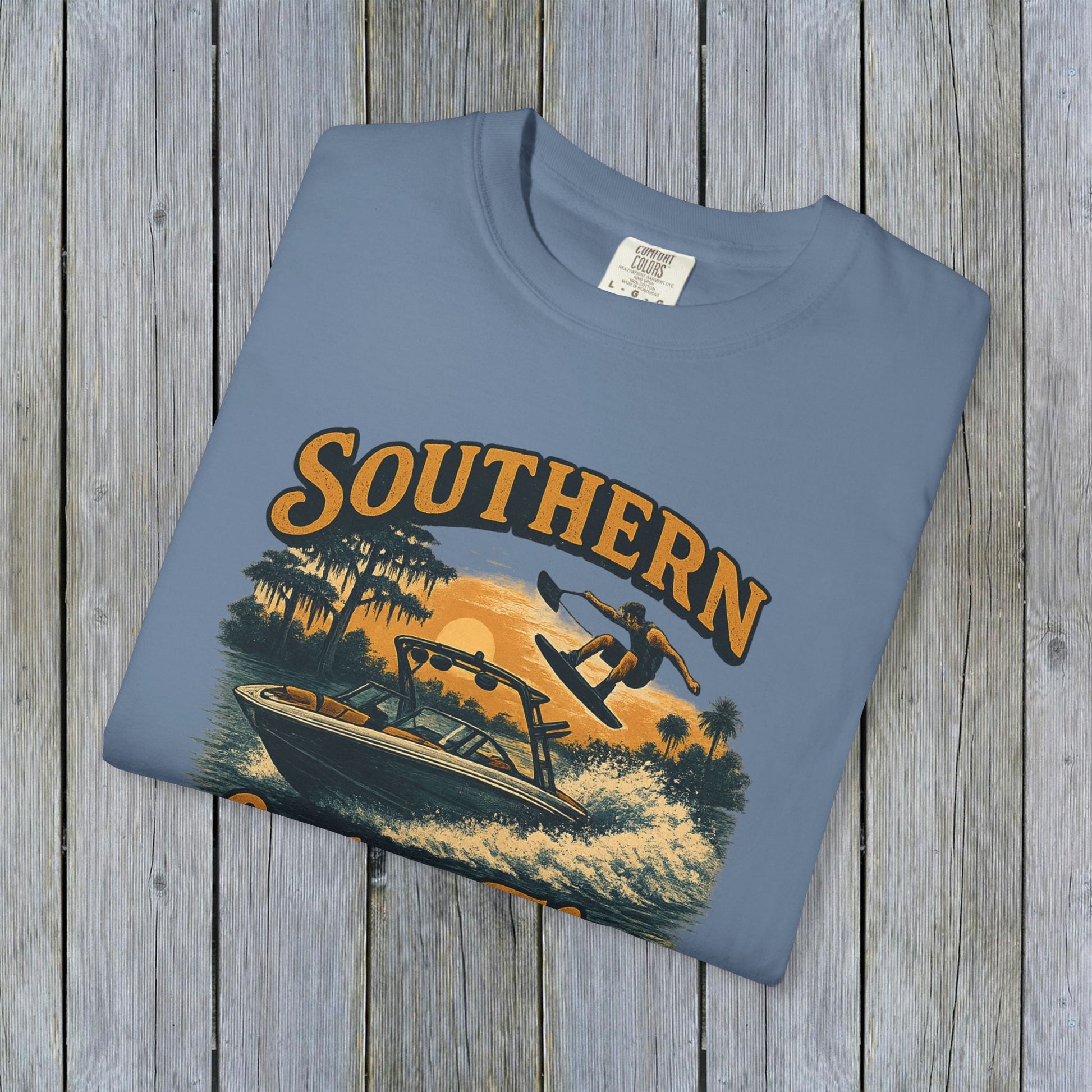 Folded Southern Lake Flow T-Shirt displayed on a wooden surface, highlighting the vibrant graphic and eco-friendly materials.