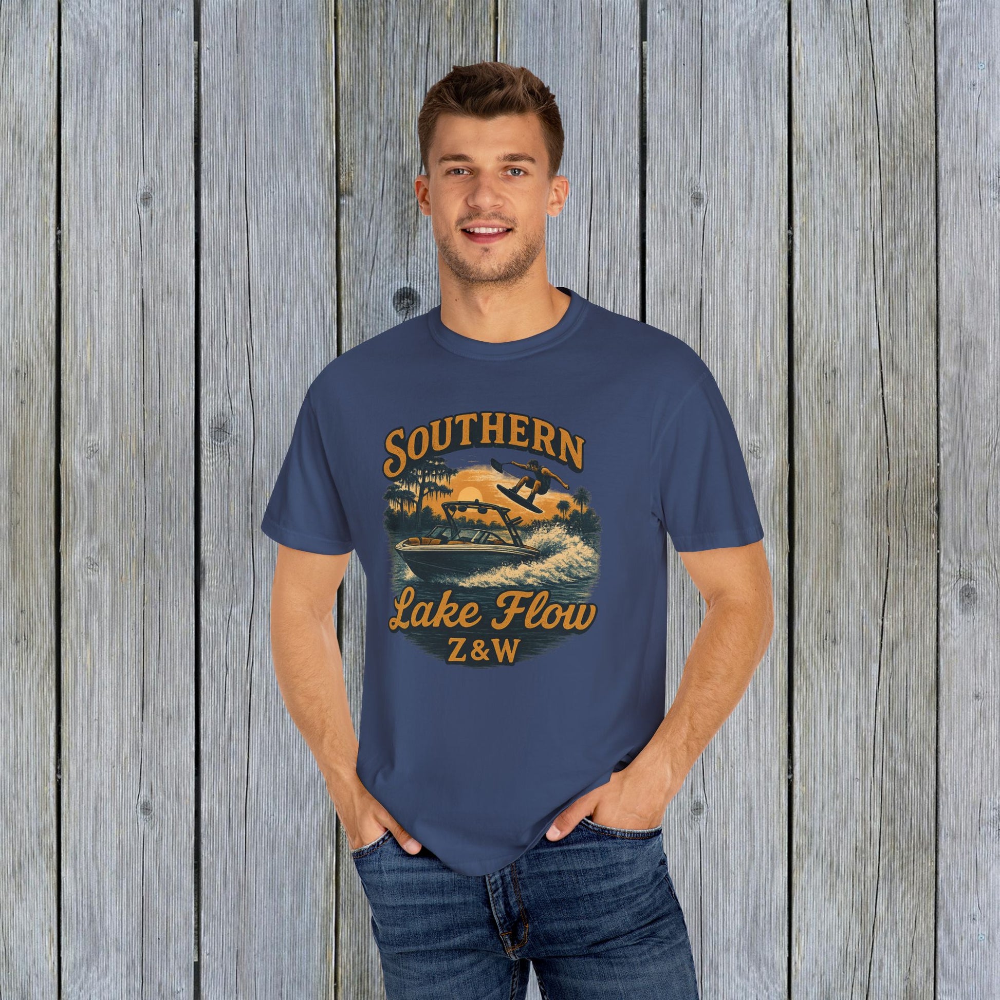 Model wearing the Southern Lake Flow T-Shirt in navy blue, featuring an illustration of a boat and wakeboarder, highlighting its eco-friendly 100% US cotton material and stylish look.