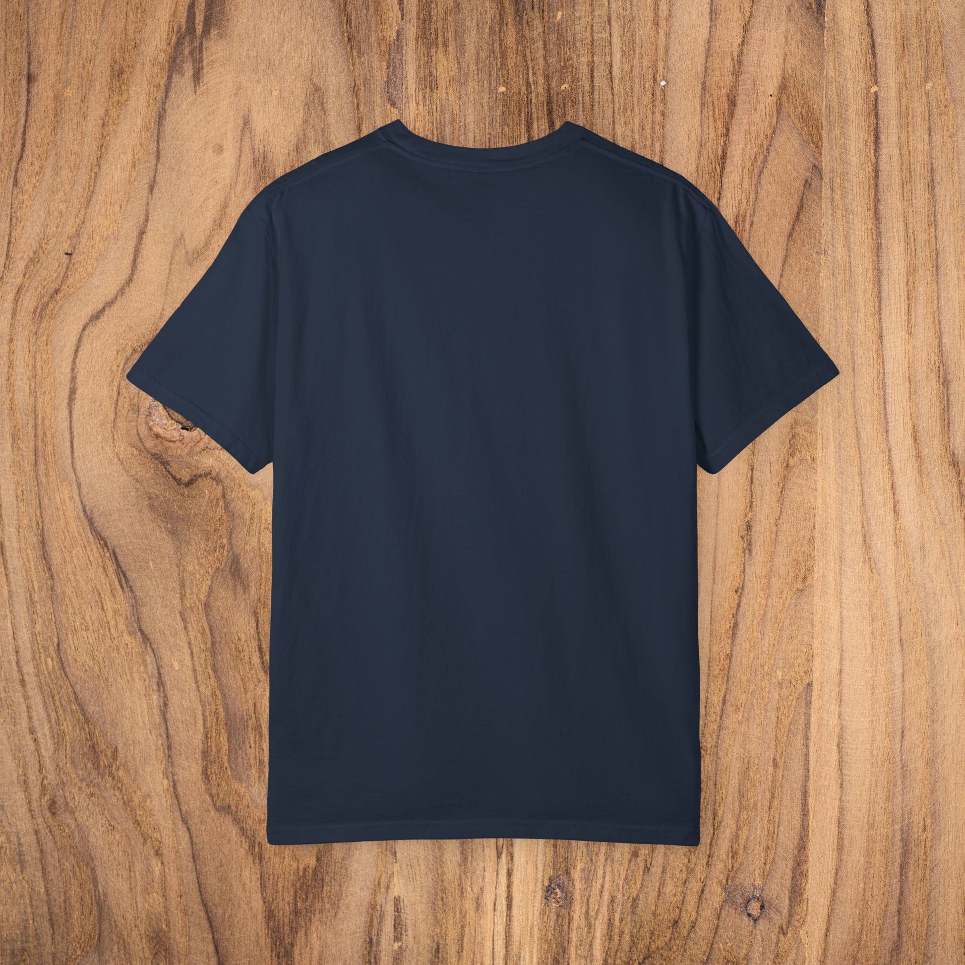 Back view of a navy blue Unisex Sunset Palm Tree T-Shirt - Vibrant Garment-Dyed Cotton Tee for Men & Women displayed on a wooden background.