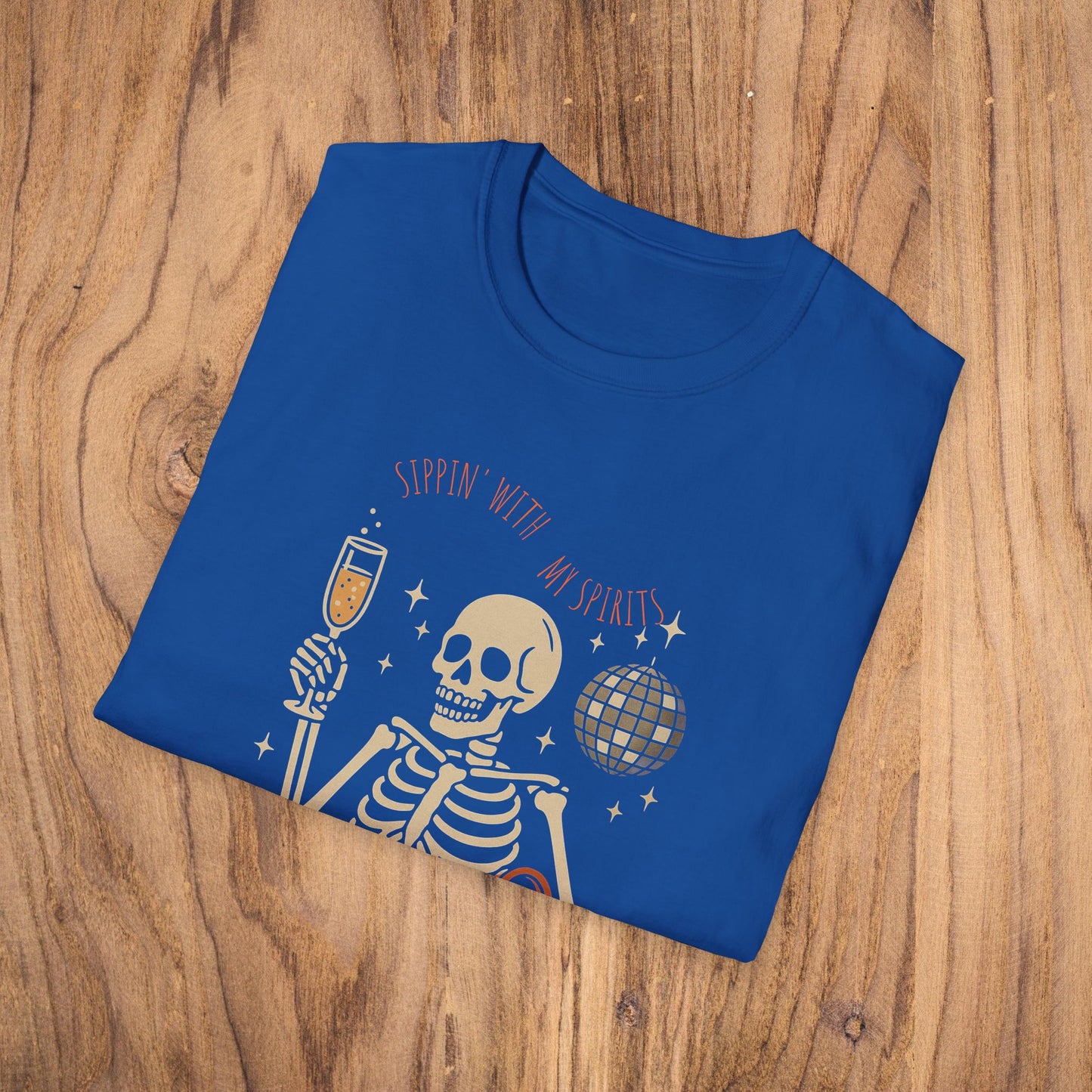 Folded Spooky Spirits Graphic Tee in vibrant blue color, displaying a lively skeleton with a drink and disco ball for Halloween fun.