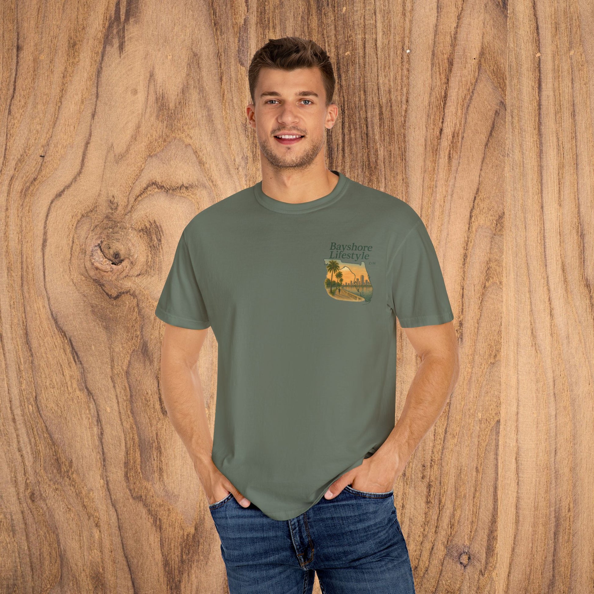 Bayshore Lifestyle Tee - 100% Cotton Lightweight Fabric, Ribbed Neck, Sizes XS-5XL - Model wearing a green t-shirt showcasing the front graphic on wooden background.
