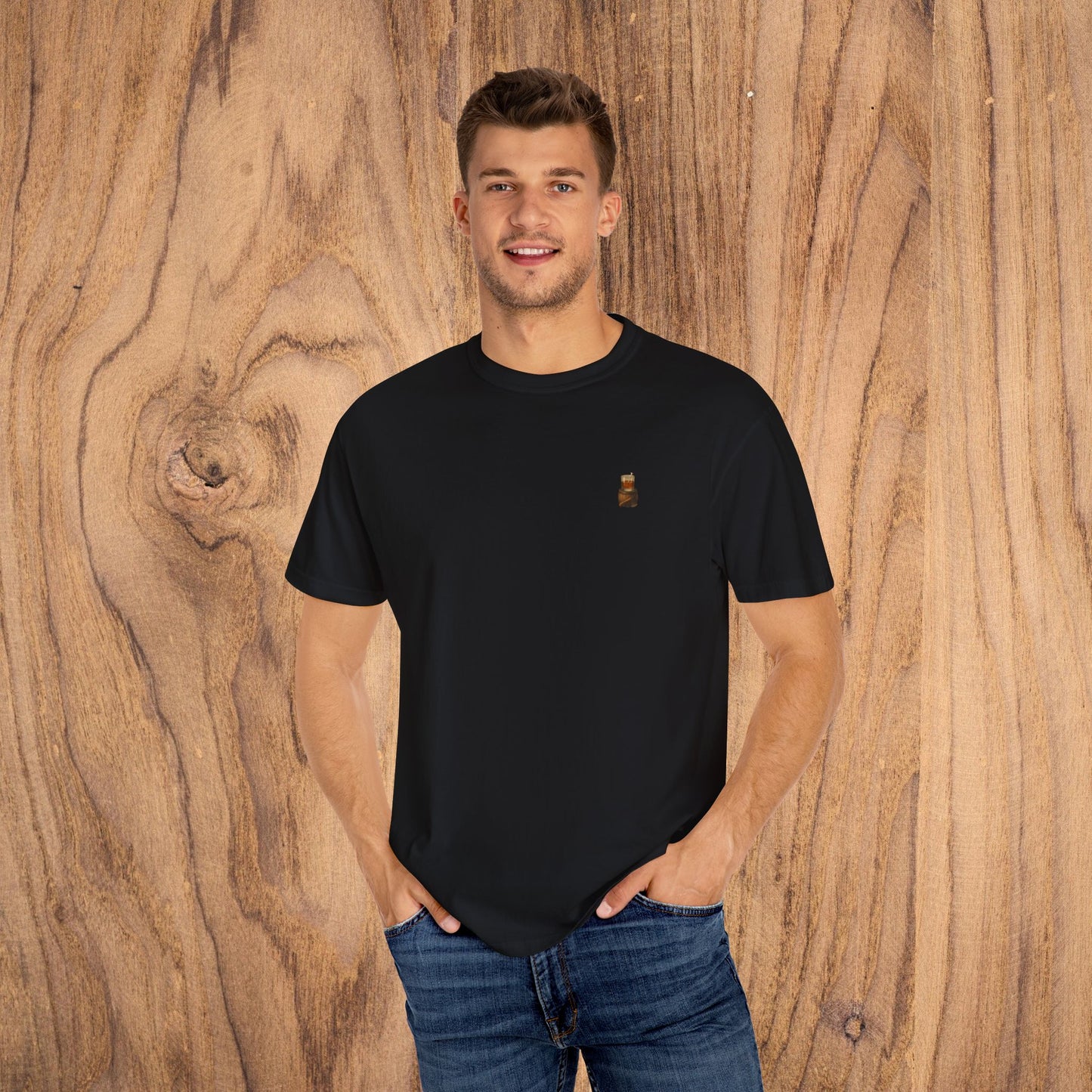 Man wearing a Premium Southern Made T-Shirt in black, standing casually with hands in pockets against a wooden backdrop.