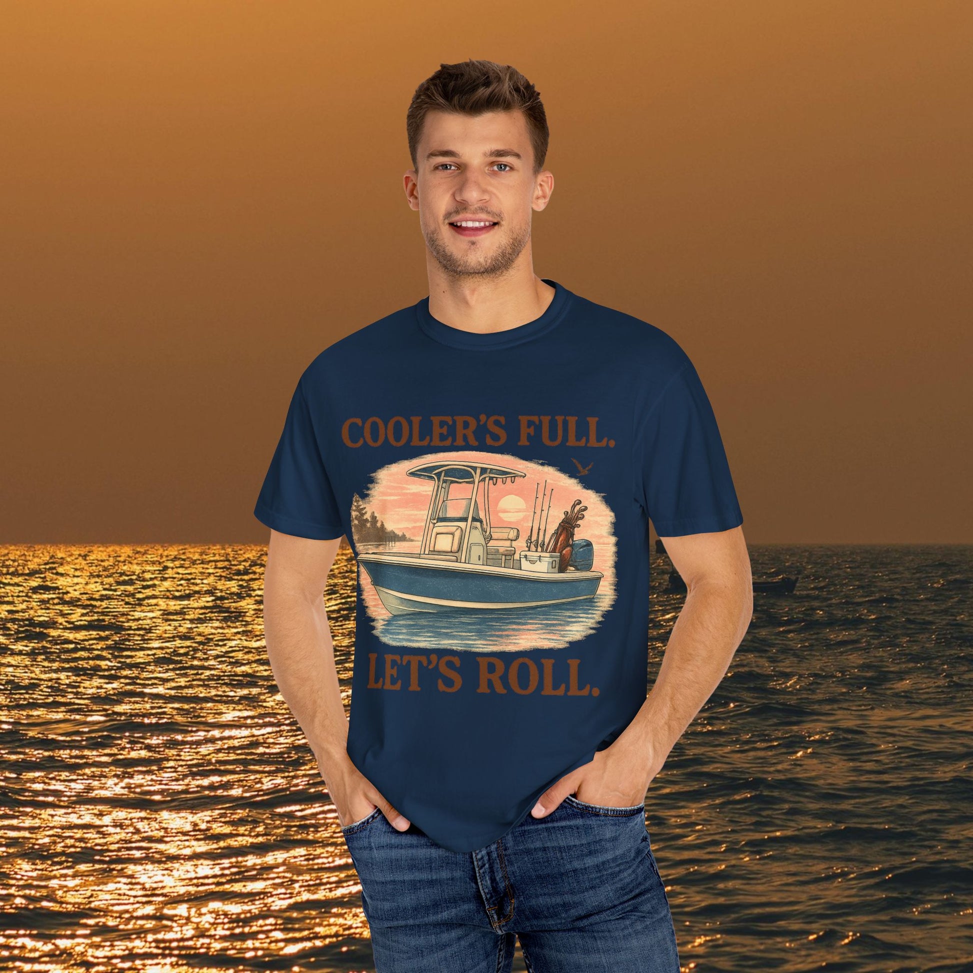Male model wearing the Men's & Women's Durable Cotton Full Tee in navy, featuring a fishing boat illustration with 'Cooler's Full. Let's Roll.' text.