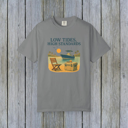 Garment-Dyed Low Tides High Standards T-Shirt in gray, illustrating a laid-back beach scene with a chair and boat. Made from soft 100% US cotton, this shirt is available in sizes S-4XL.