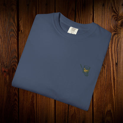 Men's Golf & Whiskey Tee folded flat, highlighting the unique logo of a whiskey glass and golf club on a blue background, ideal for casual wear or golfing outings.