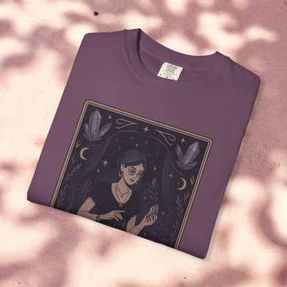 Intuitive Tarot Tee in a rich purple hue, presented on a light pink background, featuring a serene woman and mystical crystals, made from soft 100% cotton.