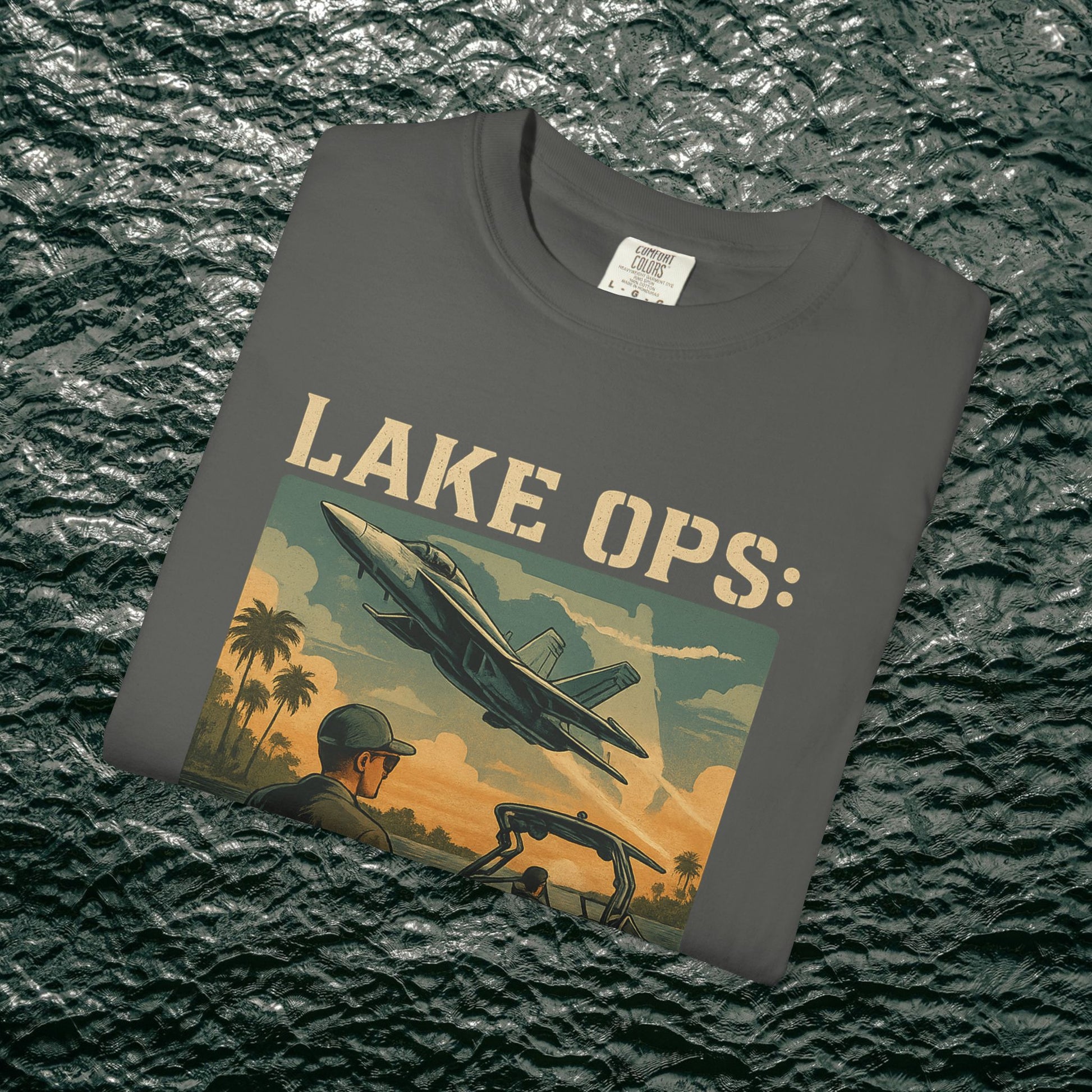 Garment-Dyed Comfort Tee For Adults in a charcoal grey shade with 'LAKE OPS:' artistic graphic depicting an aircraft, available in sizes S-4XL.