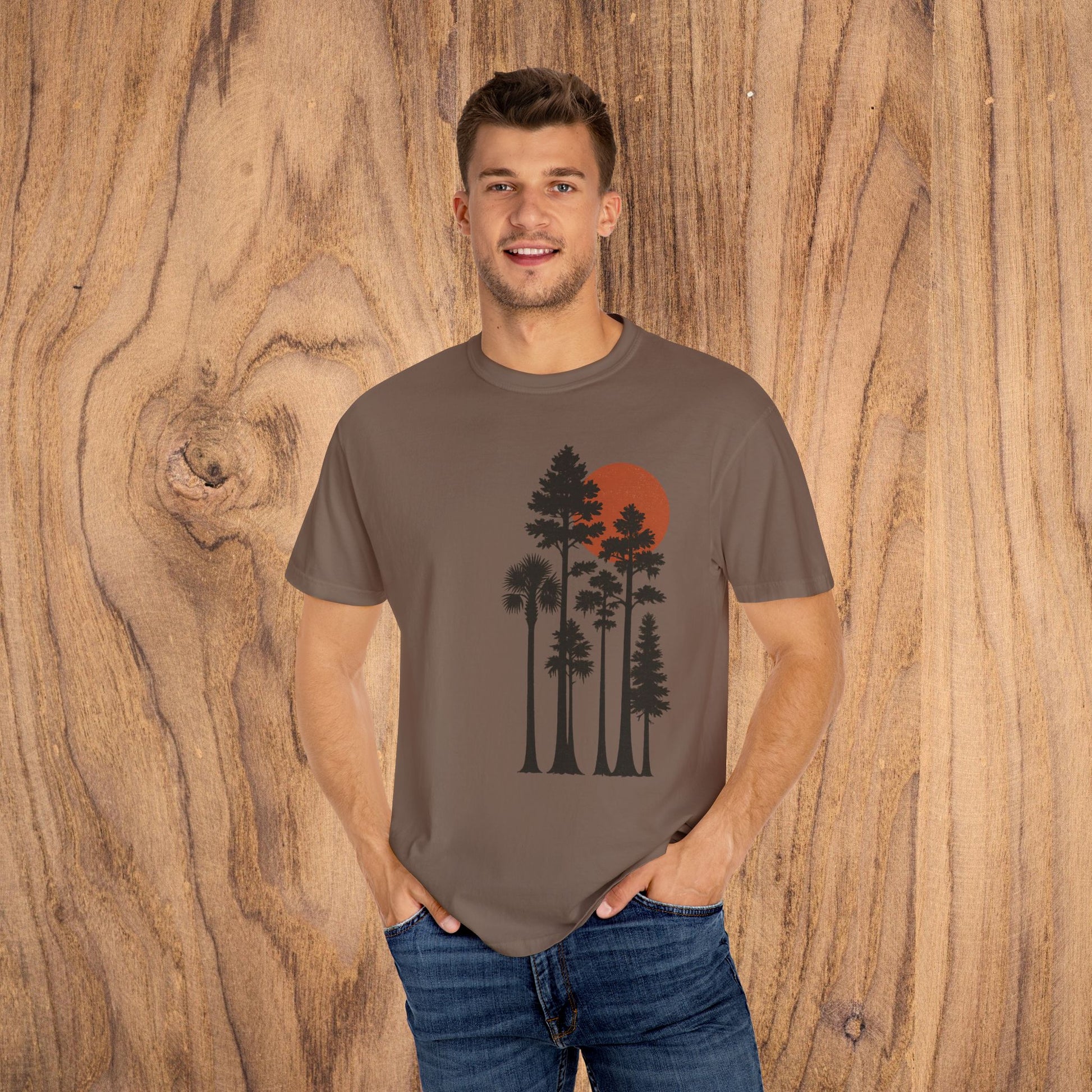 Sunset Trees Unisex T-Shirt modeled in brown, featuring a vibrant sunset and tree graphic, perfect for casual wear.