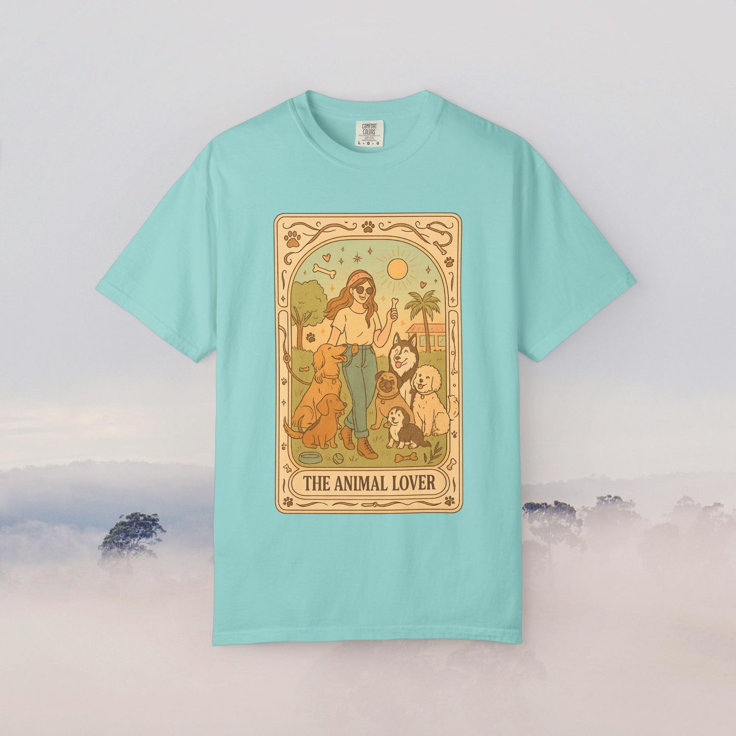 Animal Lover Tarot Tee in a vibrant teal color, featuring a detailed illustration of a woman with multiple animals against a sunny backdrop, designed for animal enthusiasts.