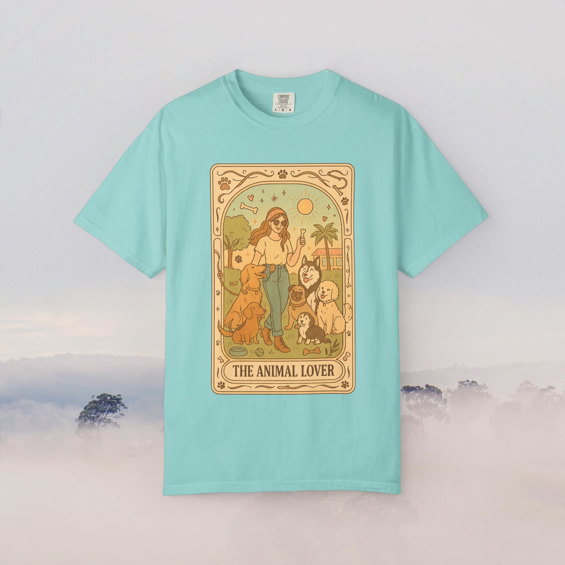 Animal Lover Tarot Tee in a vibrant teal color, featuring a detailed illustration of a woman with multiple animals against a sunny backdrop, designed for animal enthusiasts.