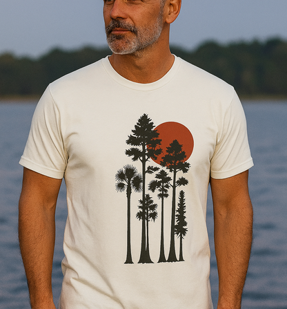 Sunset Trees Unisex T-Shirt displayed on a model by the water, showcasing the soft 100% cotton fabric and tranquil tree design, perfect for nature lovers.