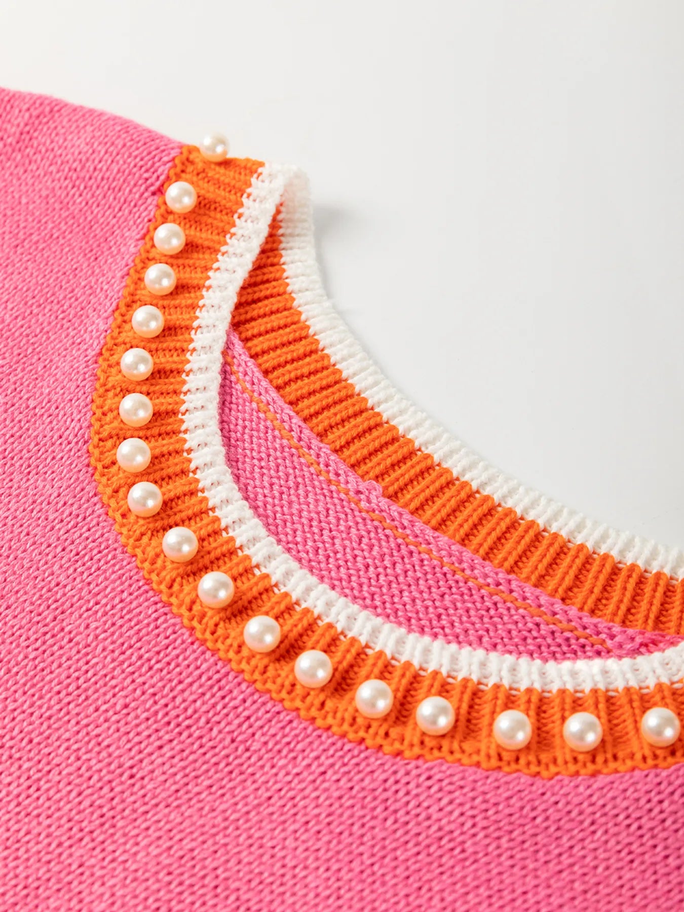 Stylish Contrast Trim Pearl Detail Sweater Tank Top featuring a vibrant pink fabric with contrasting orange trim and decorative pearl detailing.