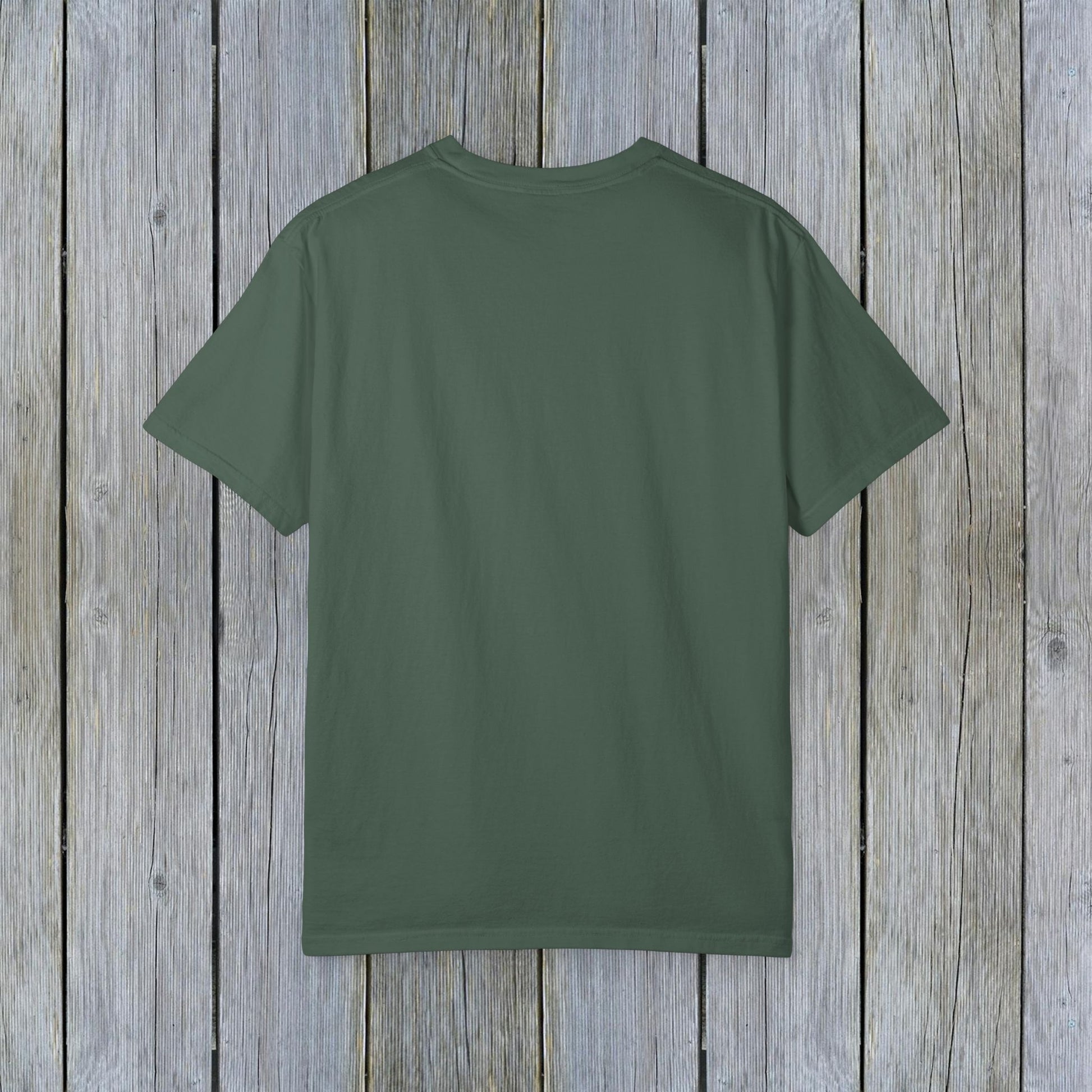 Back view of Unisex Garment-Dyed Lake Rules Tee in earthy green, perfect for outdoor adventures, presented against a textured wooden background.