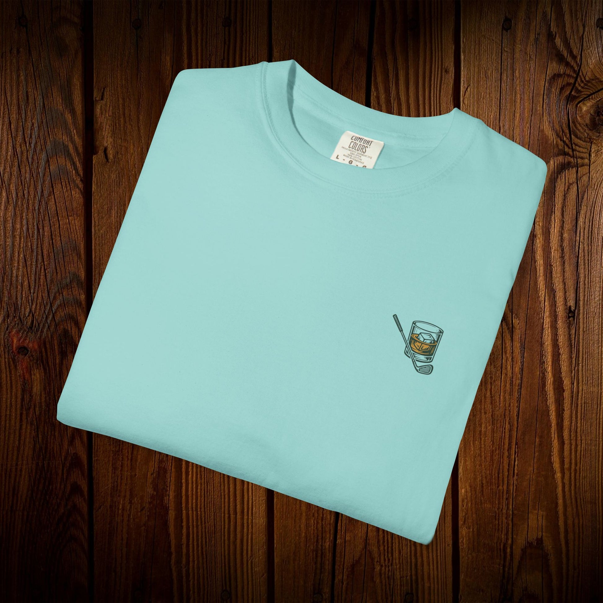 Men's Golf & Whiskey Tee showcasing a whiskey glass graphic on a light turquoise shirt, made from soft, eco-friendly cotton.