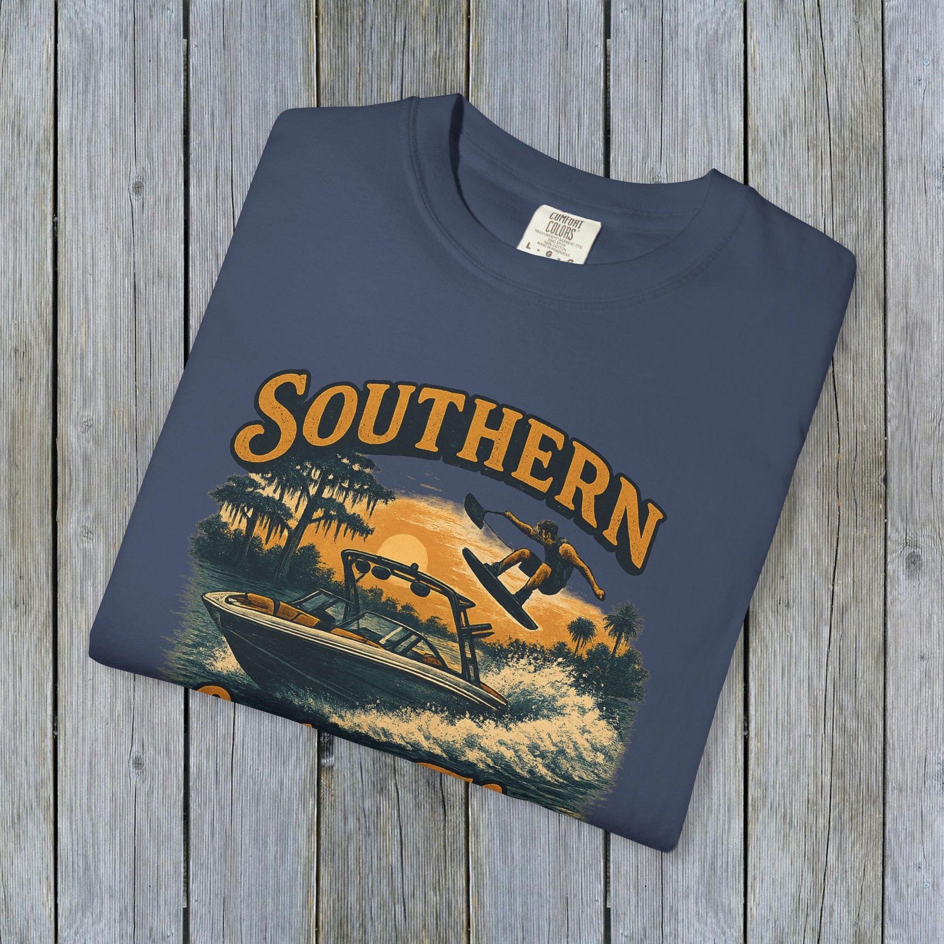 Southern Lake Flow T-Shirt displayed flat on a wooden surface, showcasing eco-friendly design and vibrant colors, crafted from 100% US cotton for durability and style.