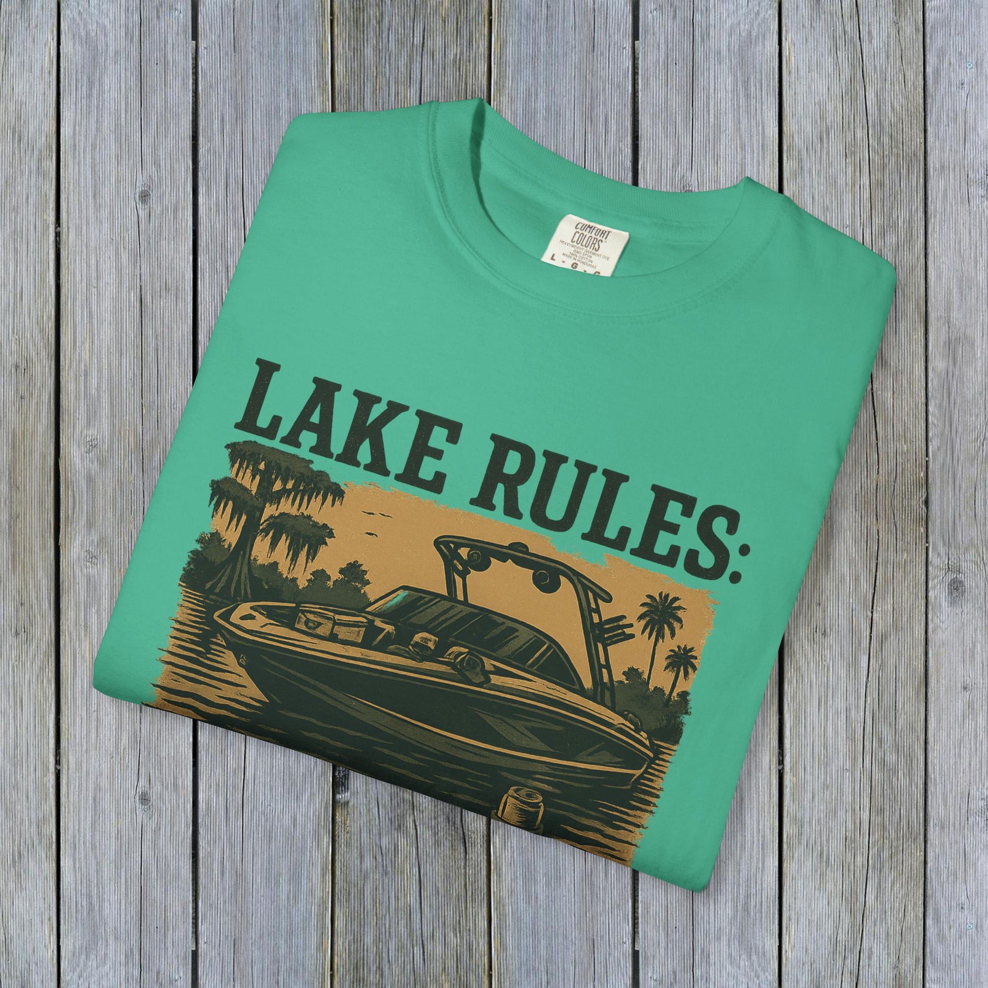 Close-up of Unisex Garment-Dyed Lake Rules Tee folded neatly, featuring the boat graphic and 'Lake Rules:' text, highlighting its unique garment-dyed fabric.