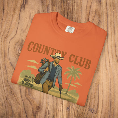 Country Club Cowboy Graphic Tee in an orange color, beautifully arranged on a wooden surface, emphasizing its cowboy graphic design.