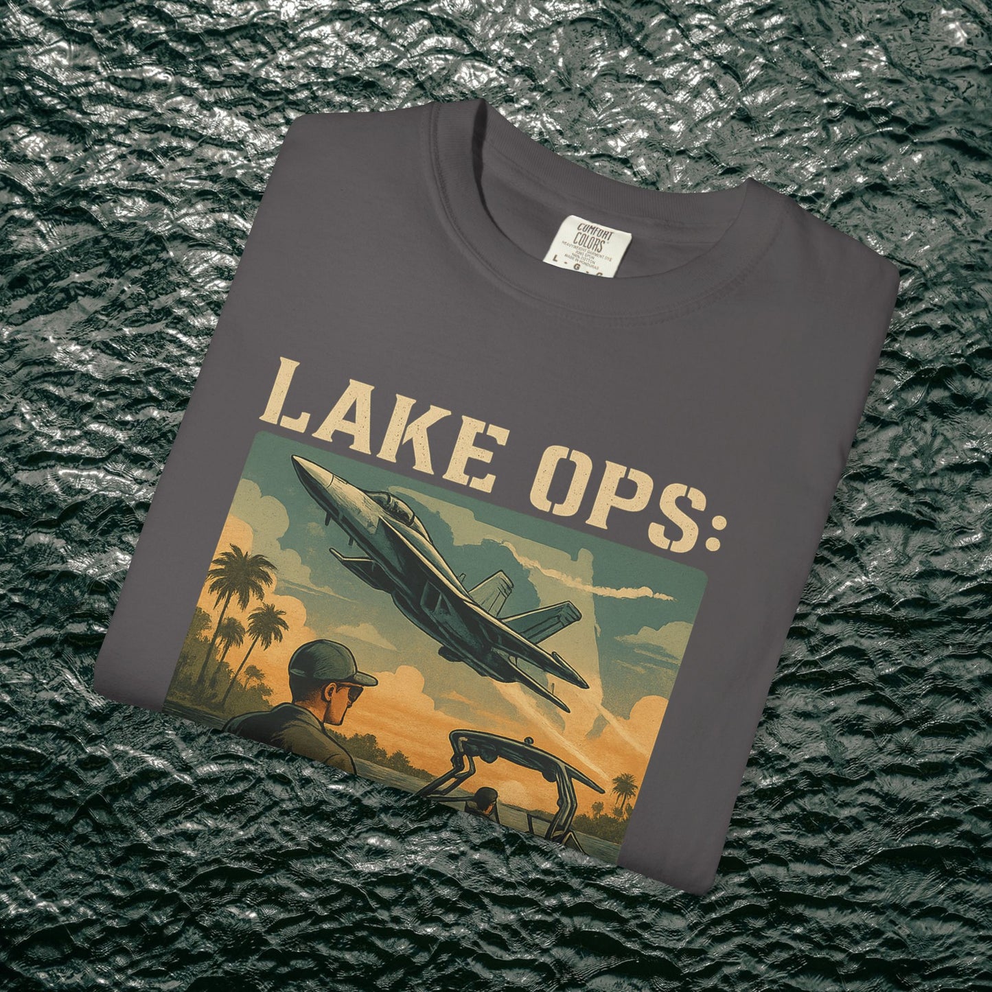 Folded Garment-Dyed Comfort Tee For Adults in dark gray displaying 'Lake Ops: Whiskey on Deck' design, offering comfort and style.