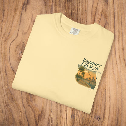 Bayshore Lifestyle Tee - Folded yellow t-shirt featuring a graphic design, laid out on a wooden surface.