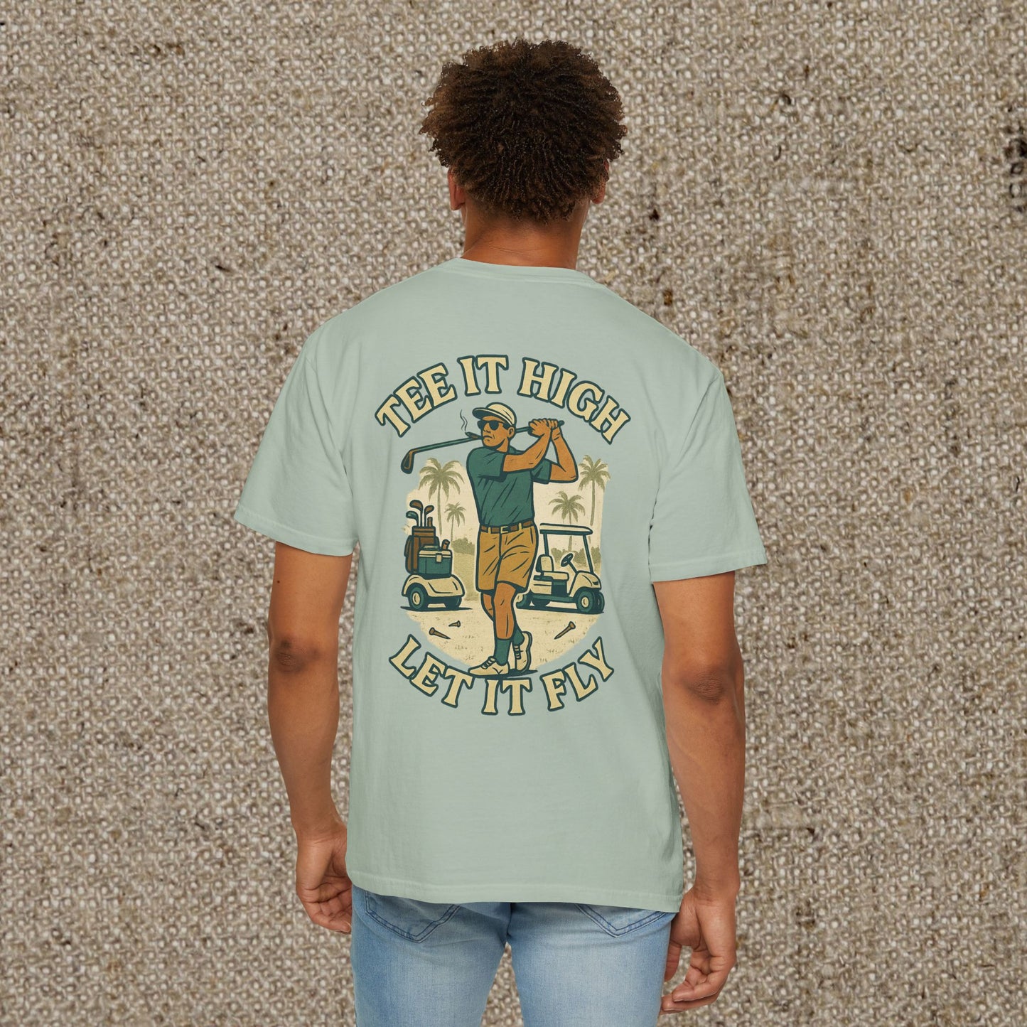 Back view of Tee It High Let It Fly Graphic Tee in light green, featuring a vibrant graphic of a golfer in action with palm trees and golf carts for a casual, fun look.
