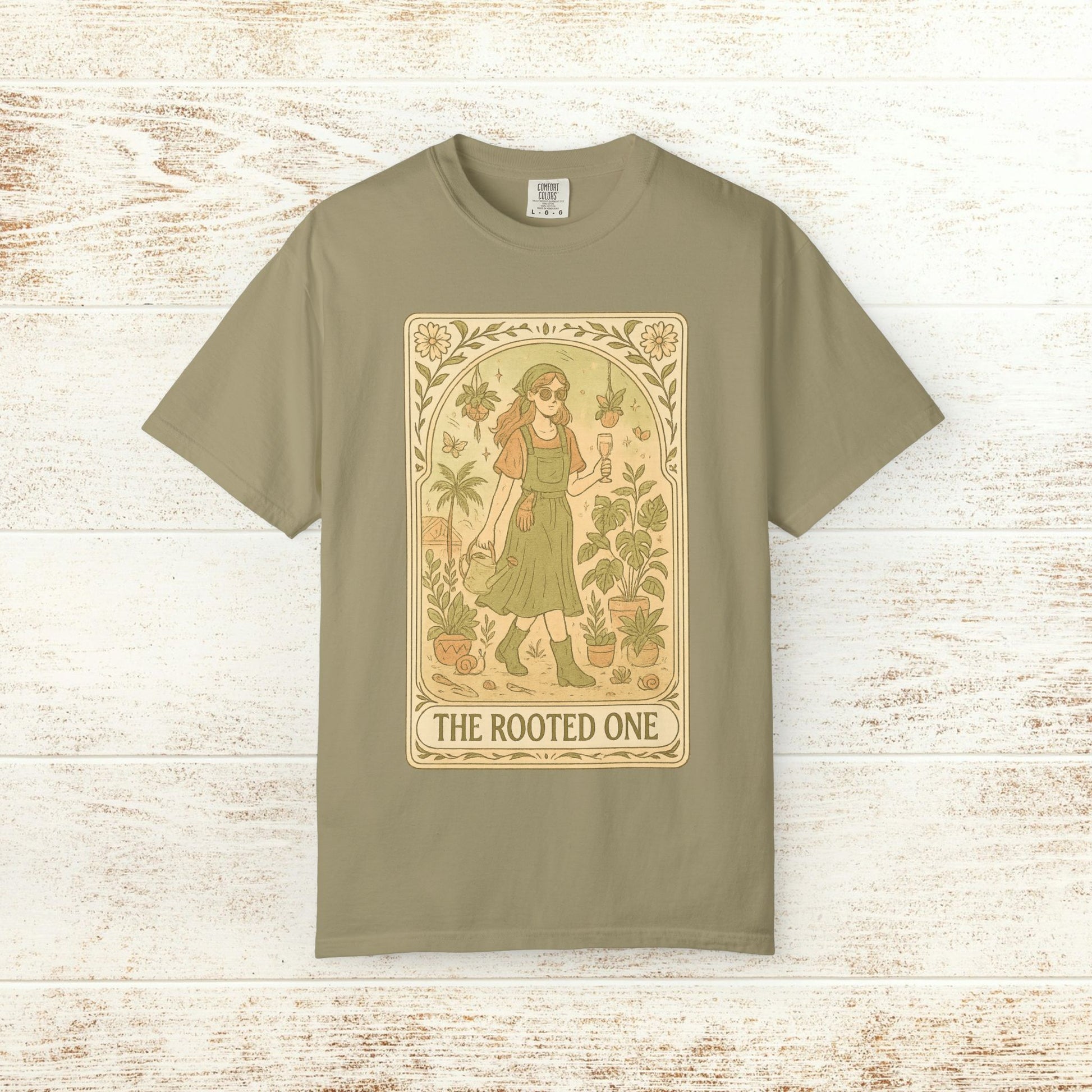 Rooted One Tarot Tee in earthy olive green, featuring a charming graphic of a woman with plants and butterflies. Made from ethically sourced cotton, sizes range from S-4XL.