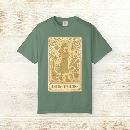 Rooted One Tarot Tee in sage green, showcasing a charming illustration of a figure among botanical elements. Made from ethically sourced cotton for conscious consumers.