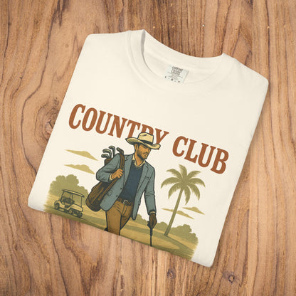 Country Club Cowboy Graphic Tee in creamy white, styled on rustic wooden background, showcasing sustainable fabric and bold graphic.
