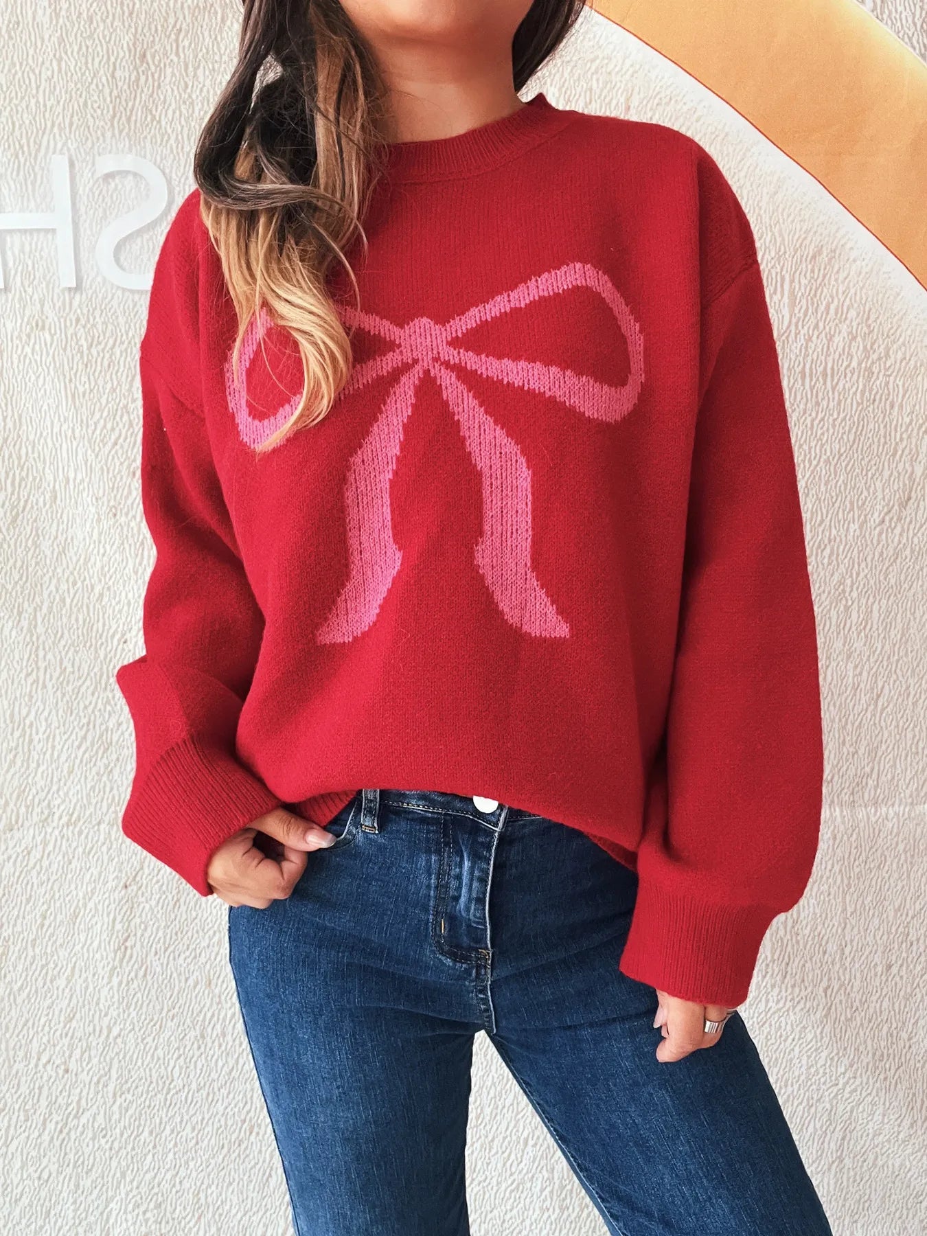 Stylish Bow Pattern Casual Long Sleeve Sweater for Effortless Everyday Wear featured on a model, highlighting the relaxed fit and unique bow pattern against a red background.